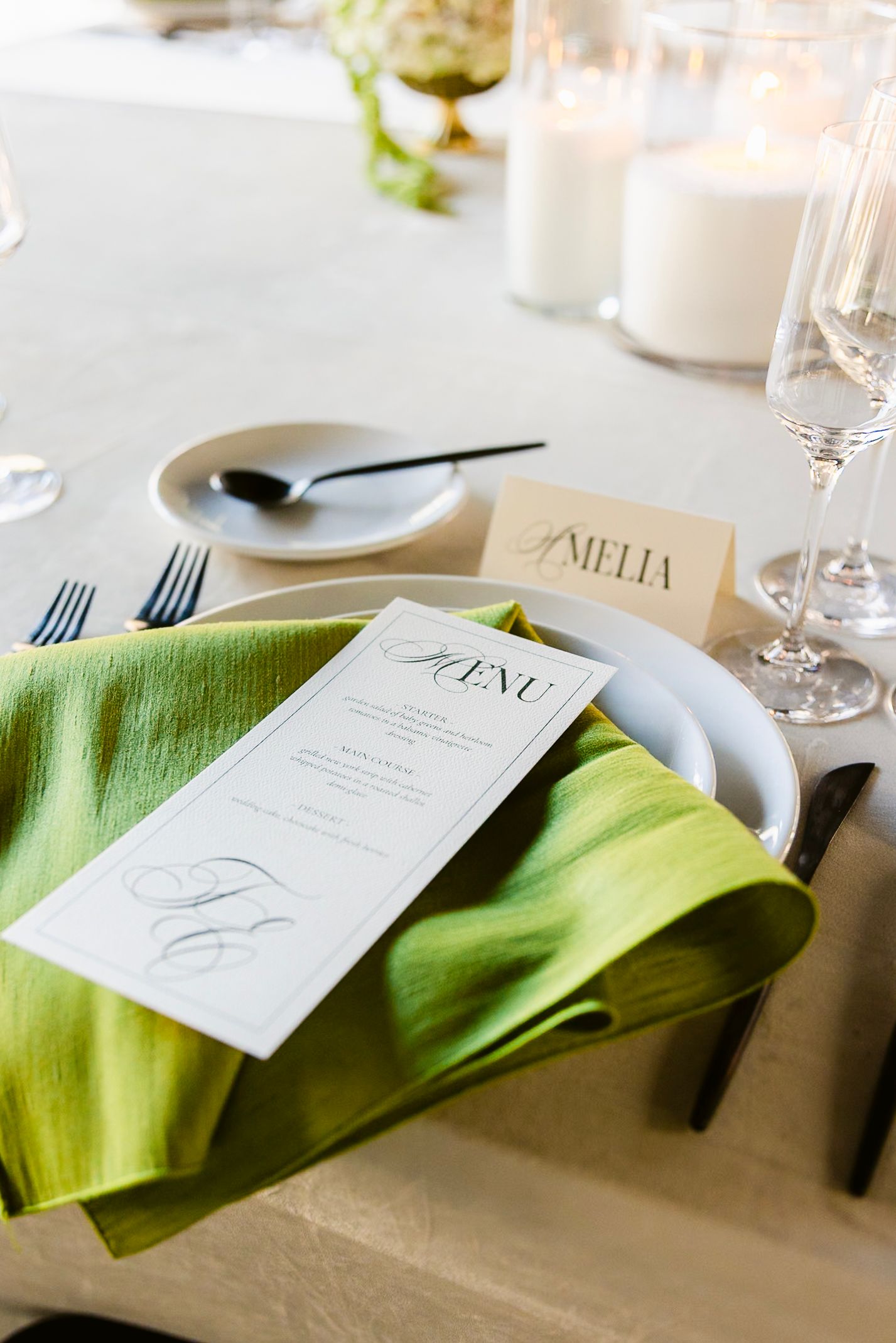 Elegant table setting with menu card, lime green napkin, and white place settings for wedding reception.