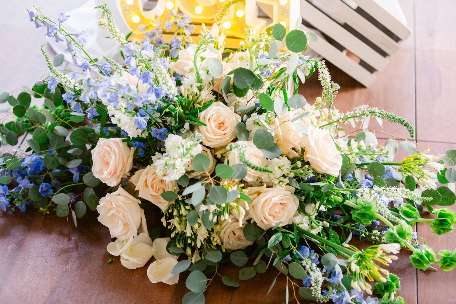 Elegant floral wedding garland with cream roses, blue delphinium, and cascading greenery creates a romantic arch display.