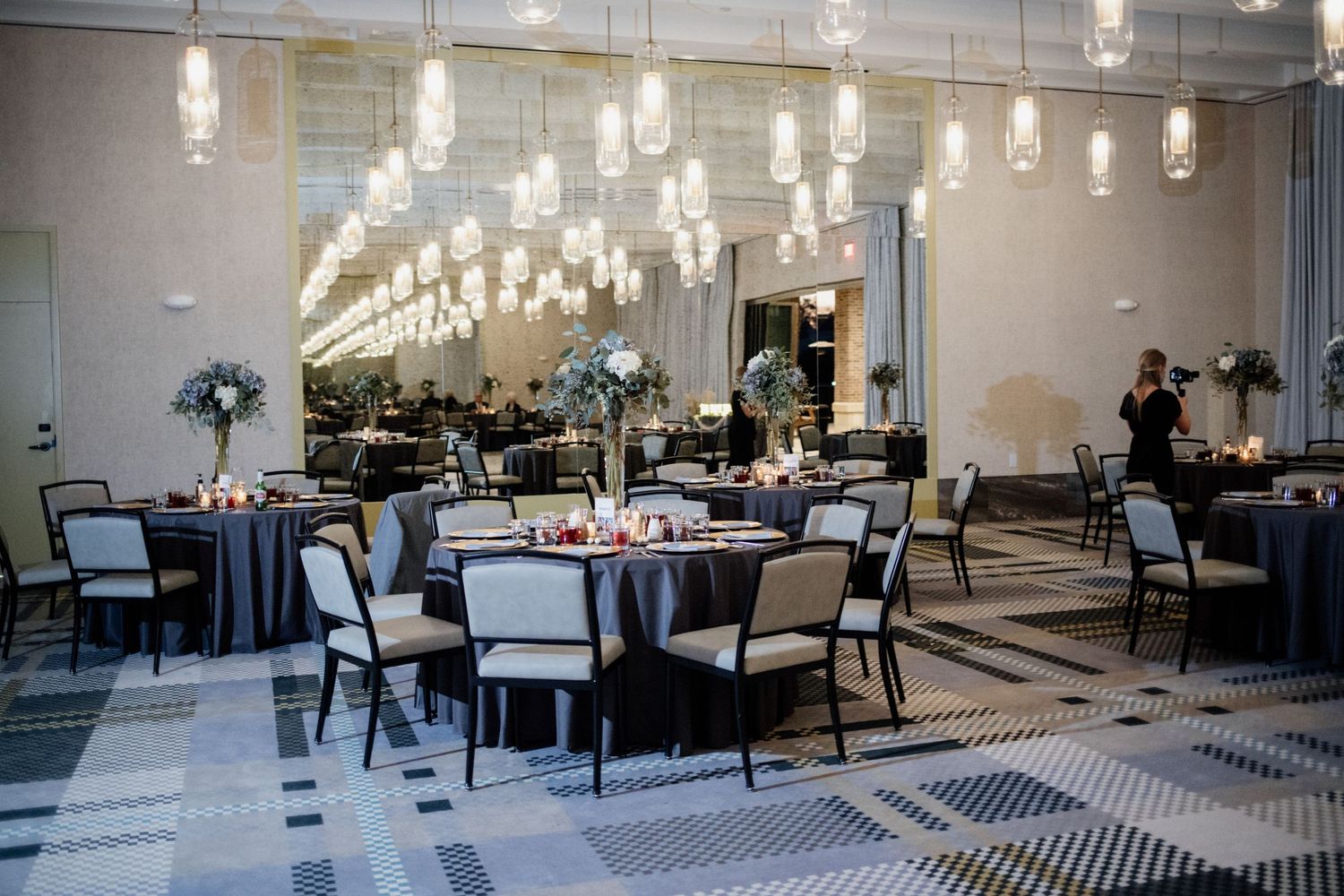Elegant wedding reception venue with hanging glass lights and round tables set for dining.