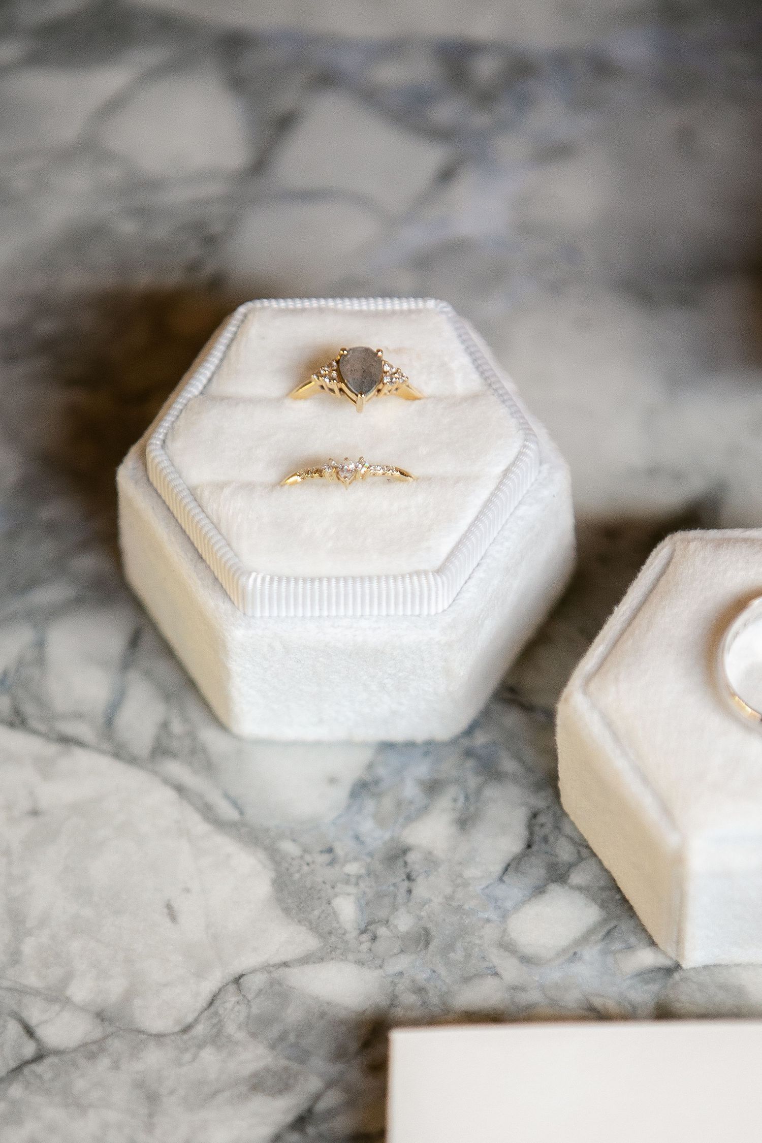 A white hexagonal ring box shown from different angles on a marble surface.