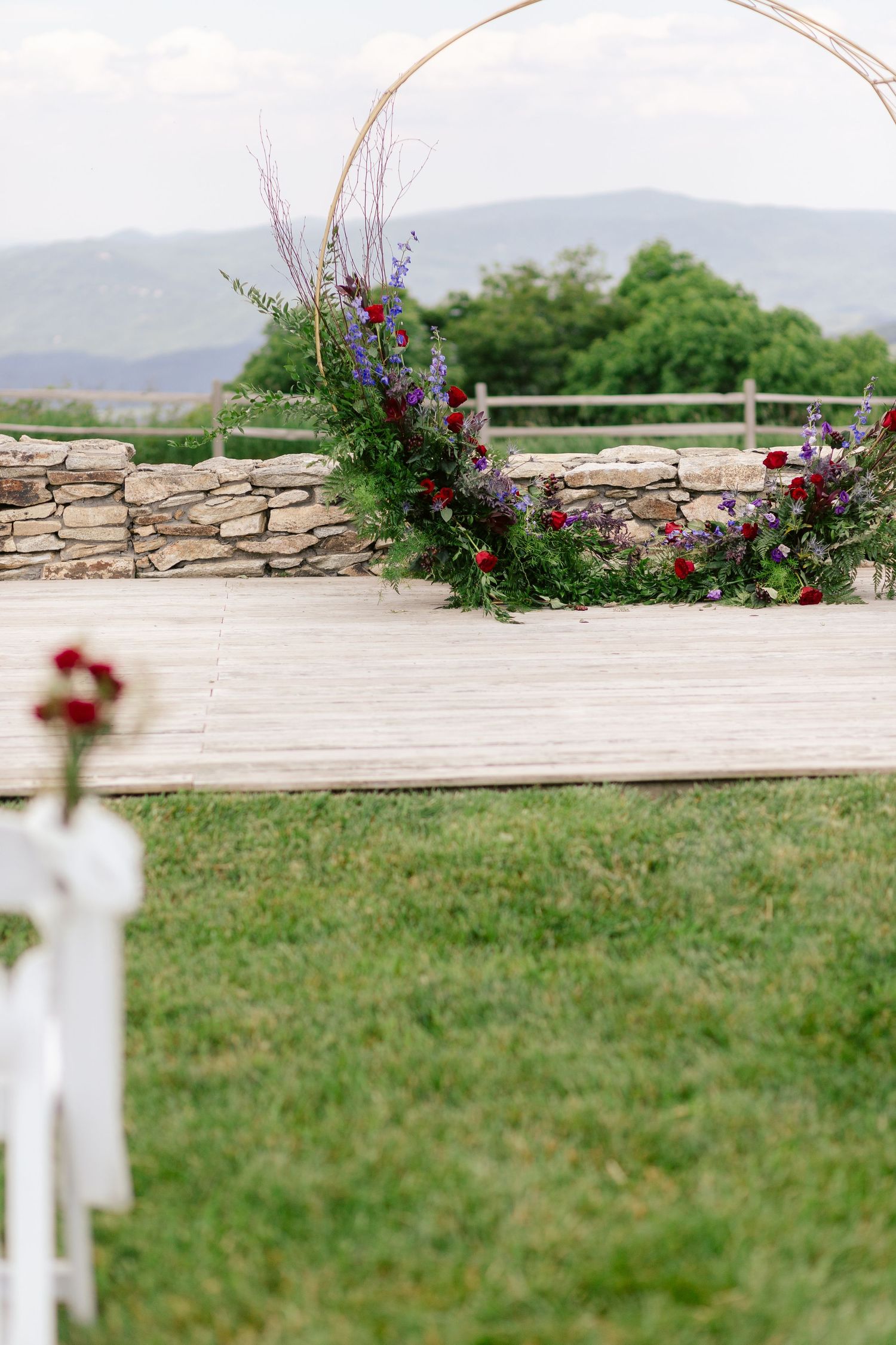 Floral arch installation on stone wall platform with mountain views.