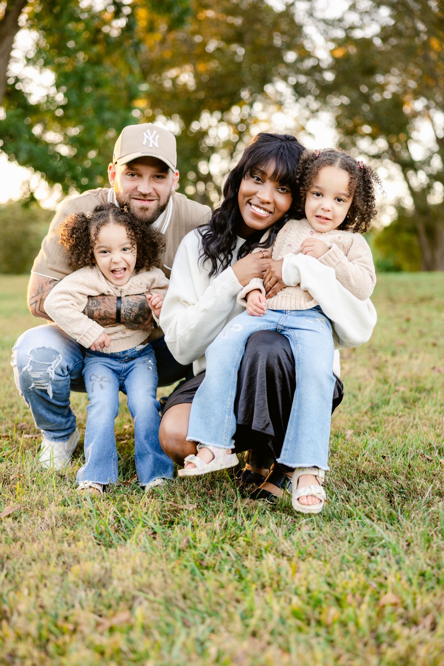 Family sitting together on grass during golden hour outdoor photo session.