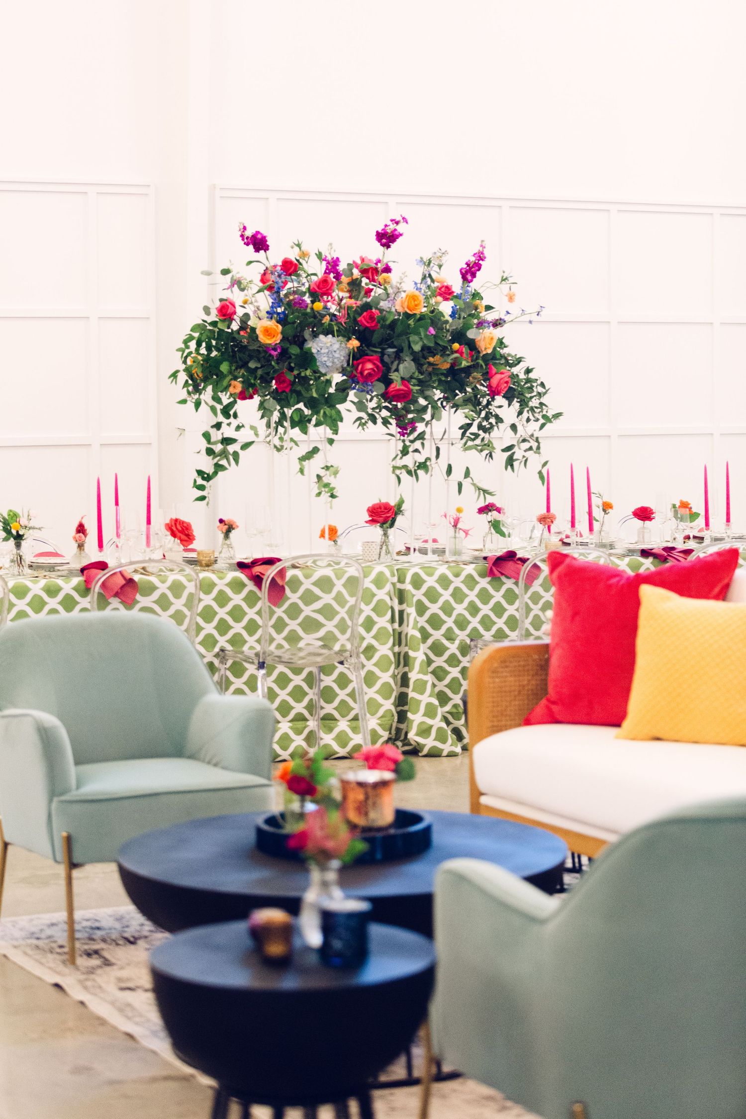Elegant lounge area with mint green chairs, red pillows, and black round tables decorated with floral arrangements.