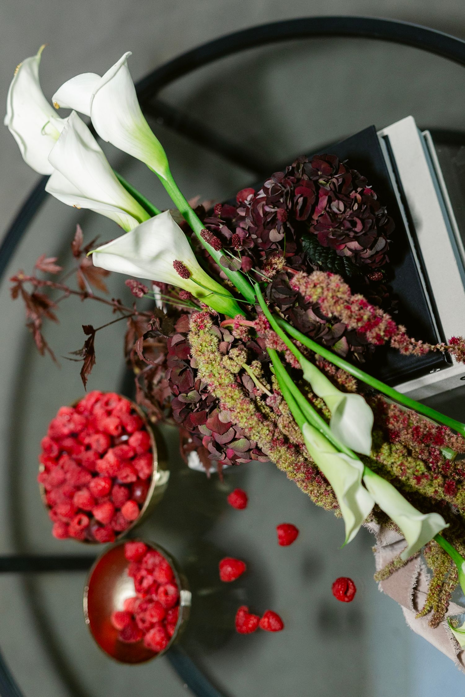 Close-up sequence showing red berries and white calla lilies in a modern floral arrangement against a dark background.