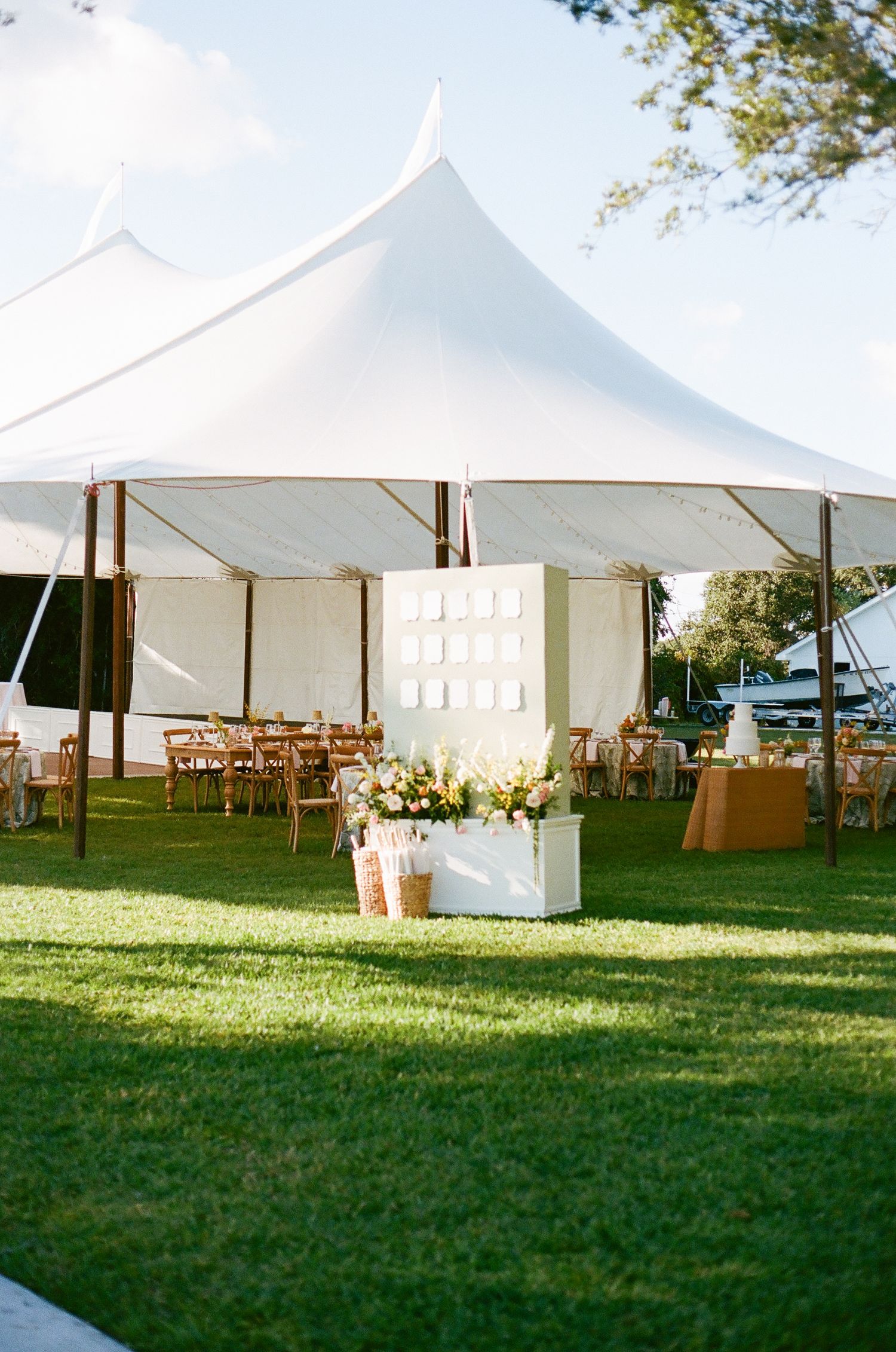 Elegant white pole tents set up on a grassy field for an outdoor event with natural lighting.