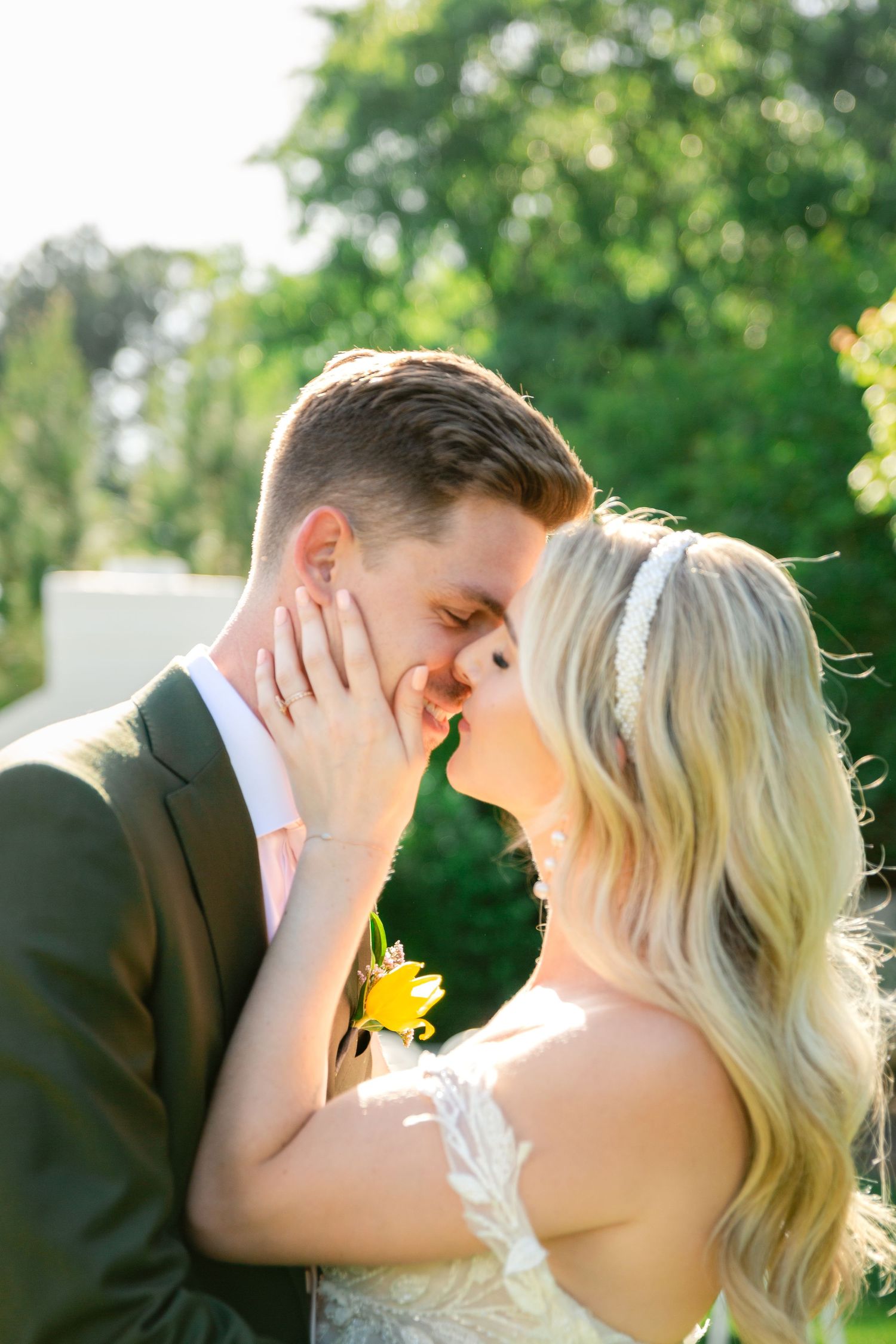 Sunlit outdoor portrait of couple embracing in formal attire.