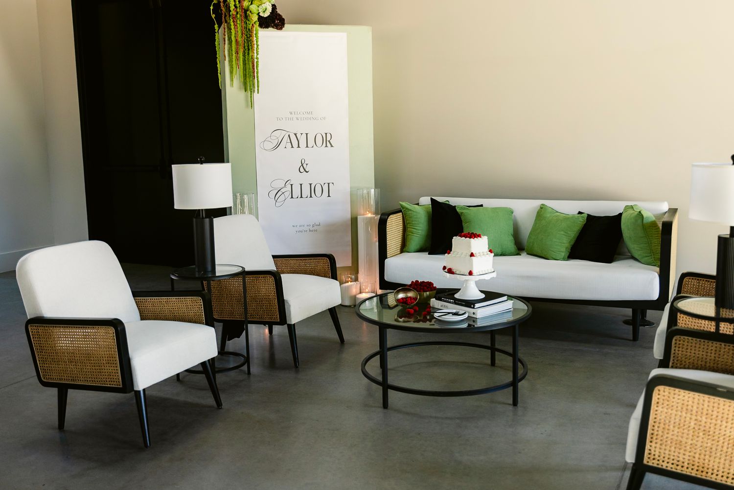 Modern living room with white sofa, green accent pillows, rattan chairs, and round coffee table in contemporary setting.