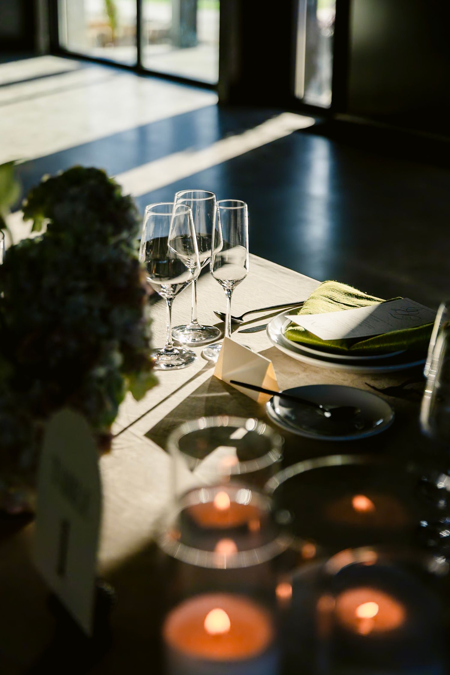 Intimate table setting with wine glasses and candles creating a moody atmosphere in dim lighting.