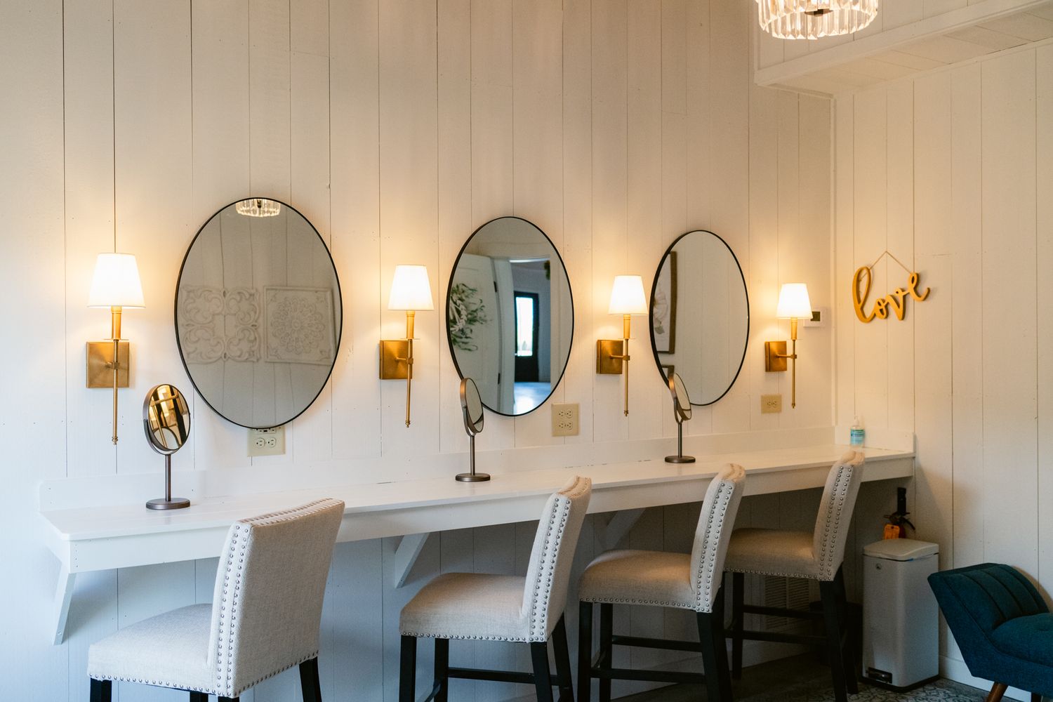 A modern bathroom interior with oval mirrors, wall sconces, and white walls featuring elegant lighting fixtures.