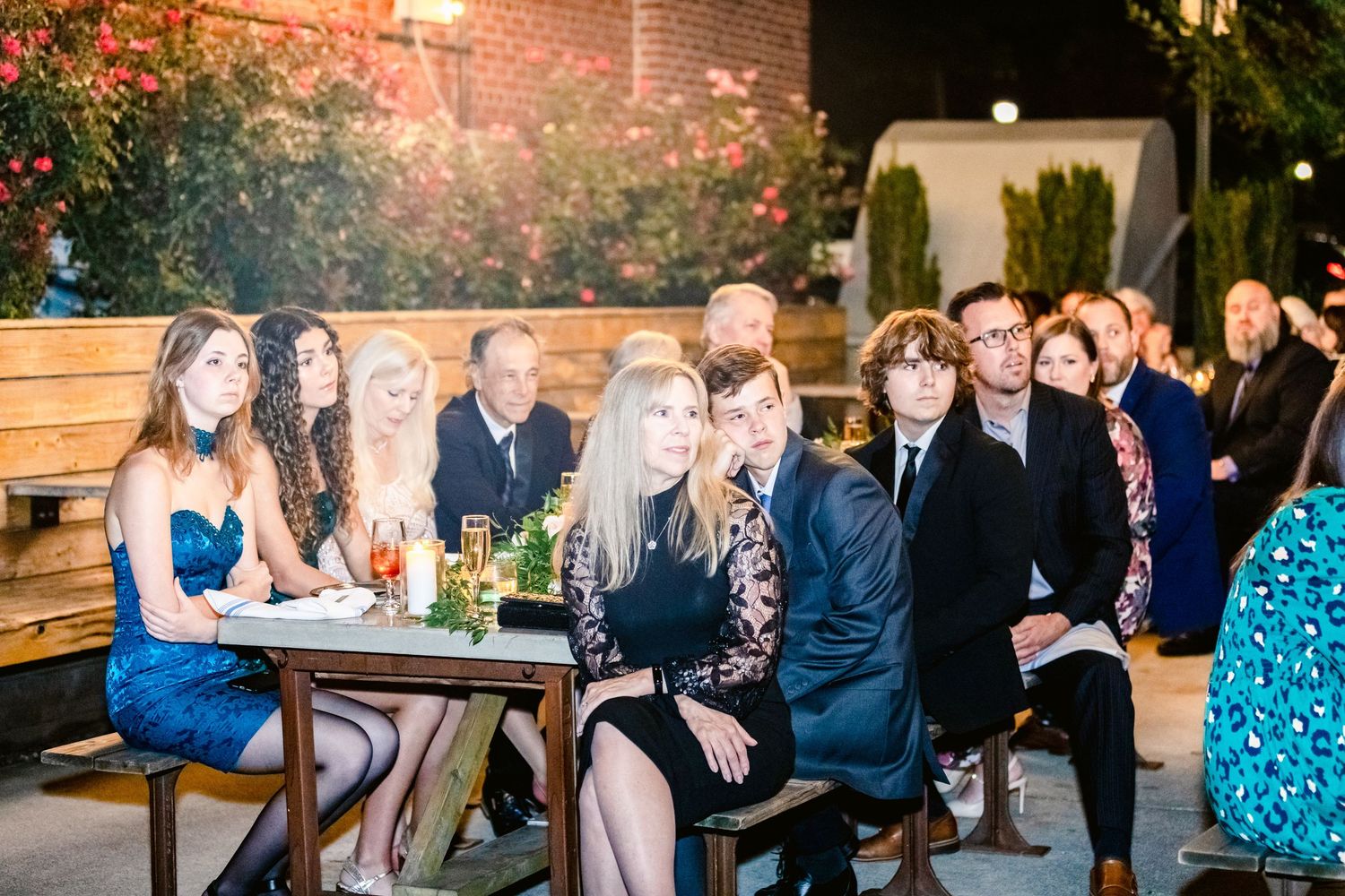 Wedding guests celebrate and mingle during a lively reception with string lights overhead.