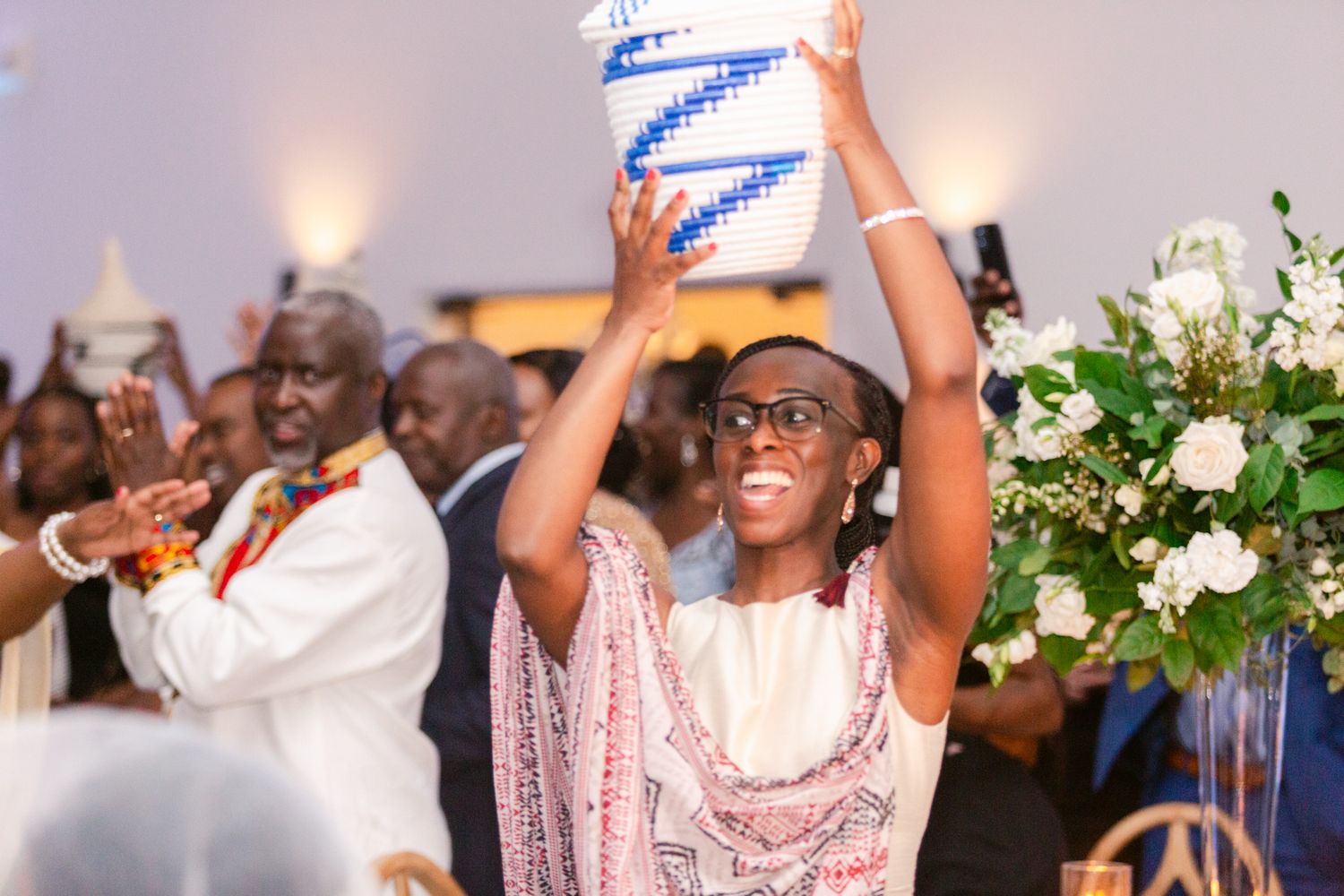 Wedding guests dancing and celebrating with raised arms at a lively reception party.