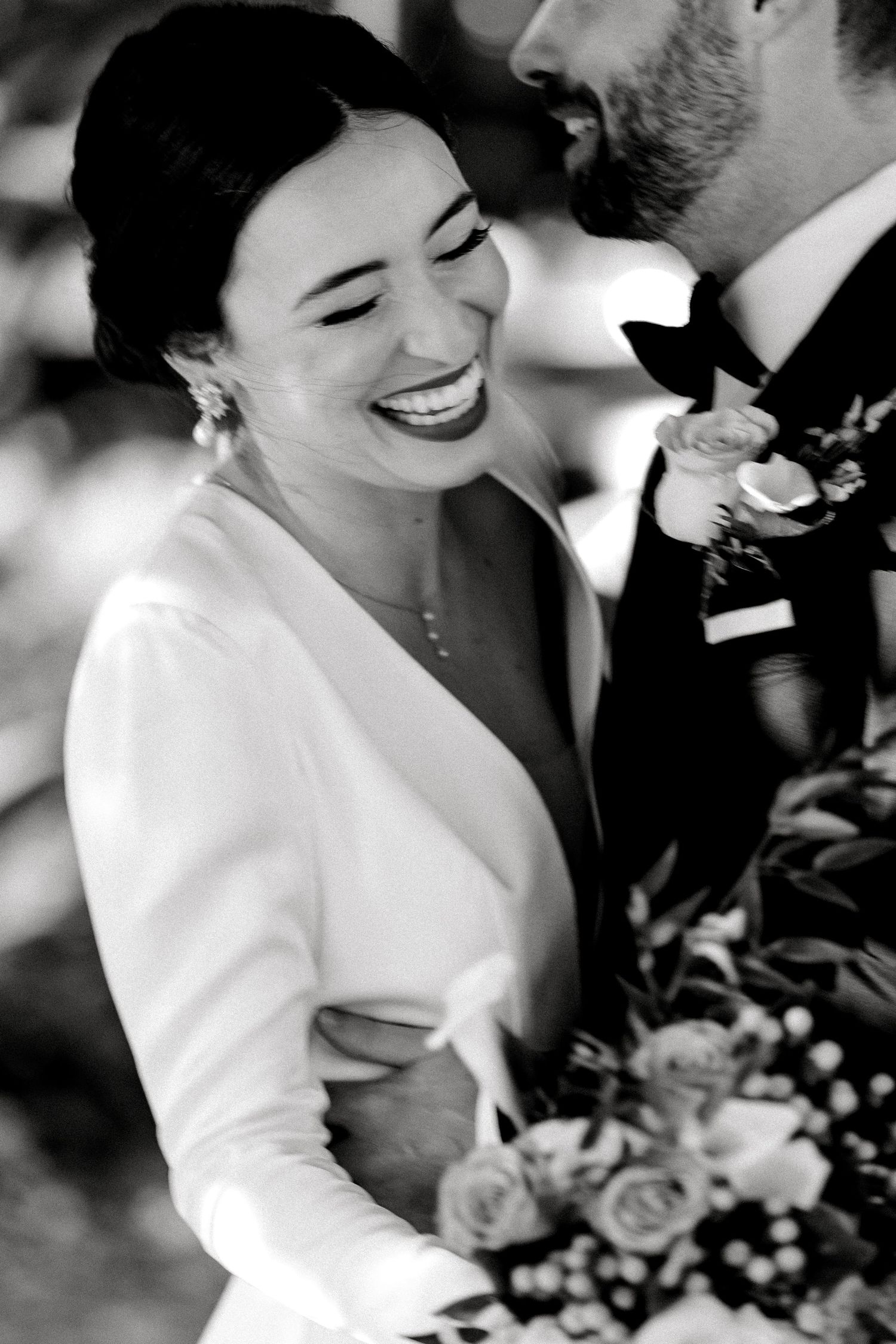 A black and white wedding portrait captures an intimate moment between newlyweds with roses.