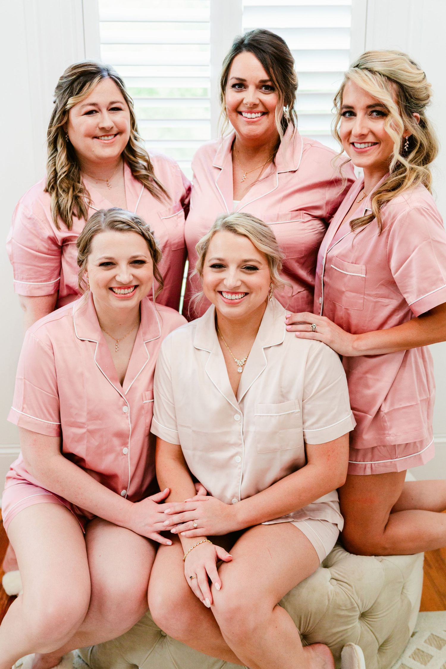 A group wearing matching pink sleepwear sits together smiling during a special celebration event.