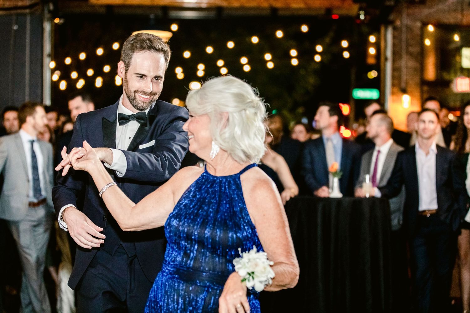 A series of four photos showing couples dancing at a wedding reception under warm string lights.