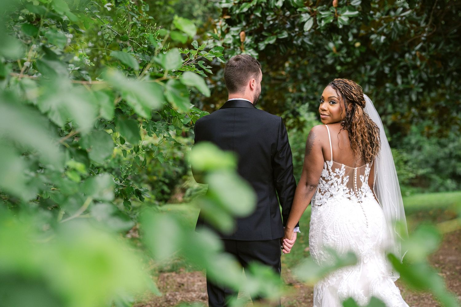 A beautiful wedding scene with a flowing white lace dress against a backdrop of green foliage.