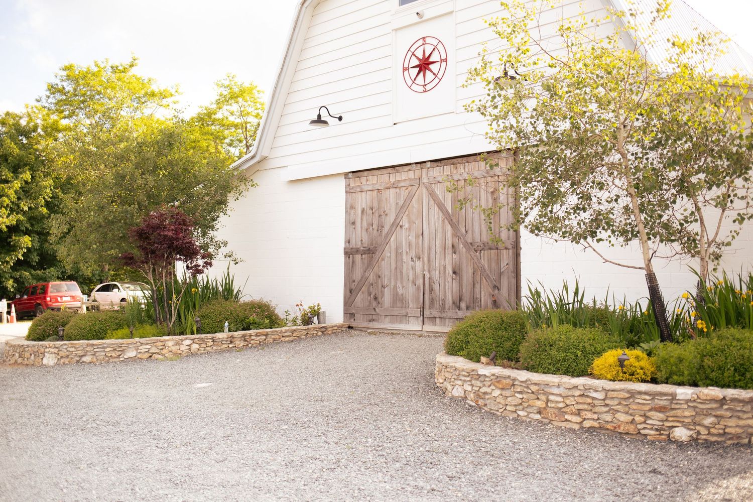 A curved stone pathway leads through a landscaped garden to a white house with flowering plants and shrubs.
