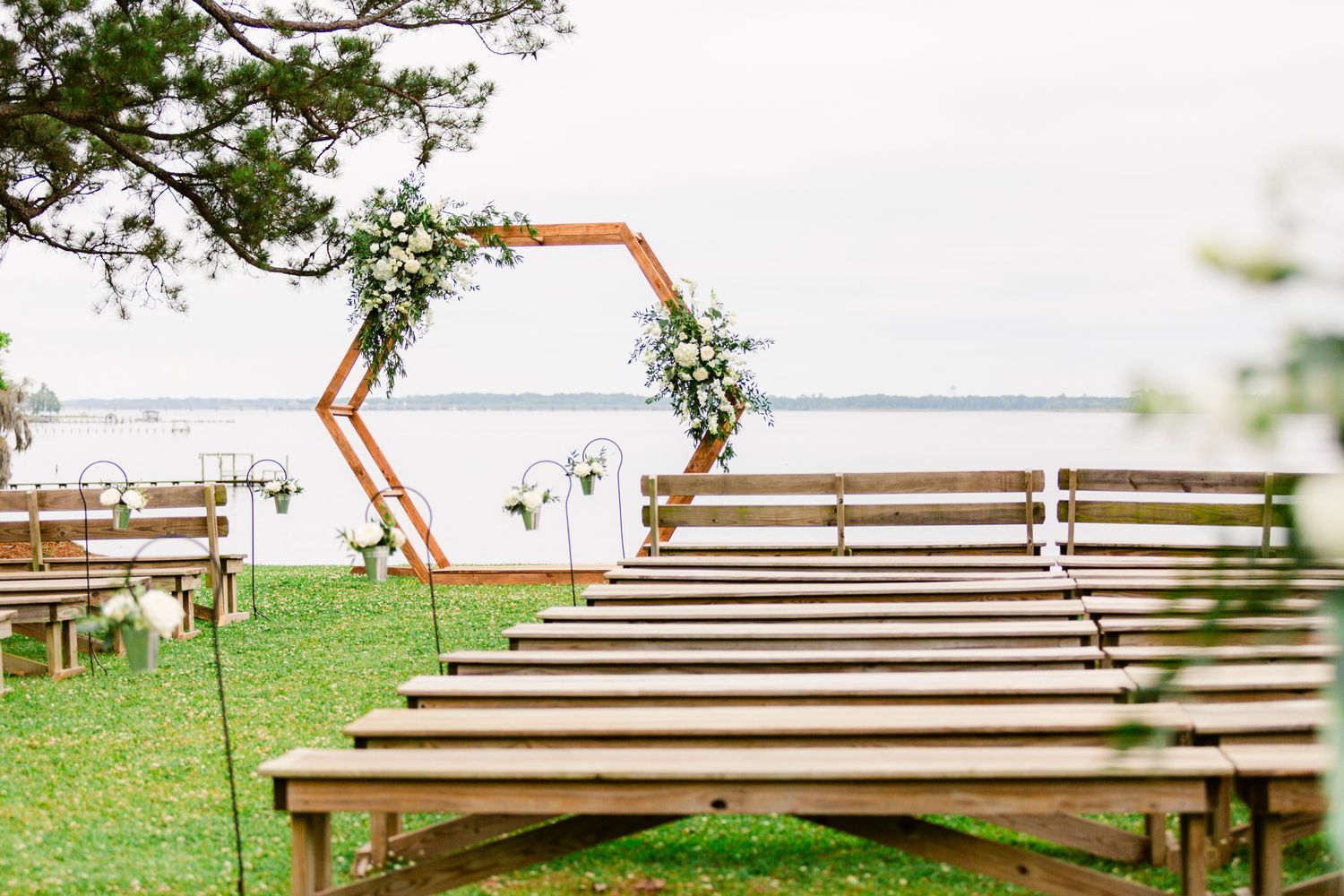 Wooden benches arranged in rows overlooking a scenic waterfront view on a grassy hill.