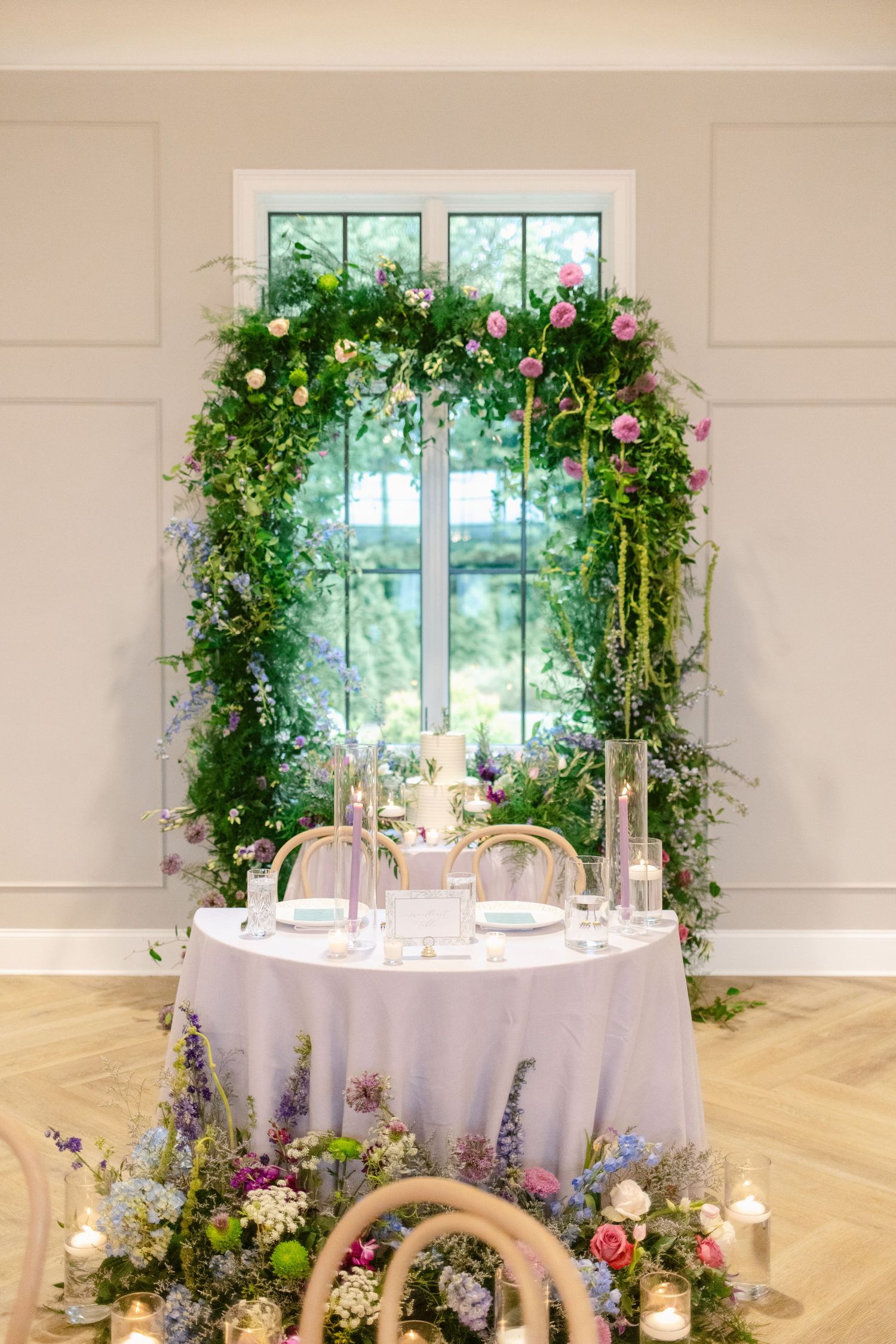 Elegant wedding reception table setup with floral archway, white tablecloth, and romantic garden-inspired decor.