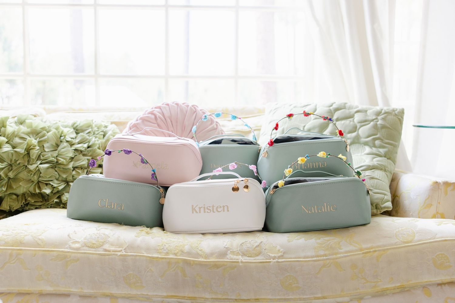 Row of soft pastel colored plush toys arranged on white bedding.