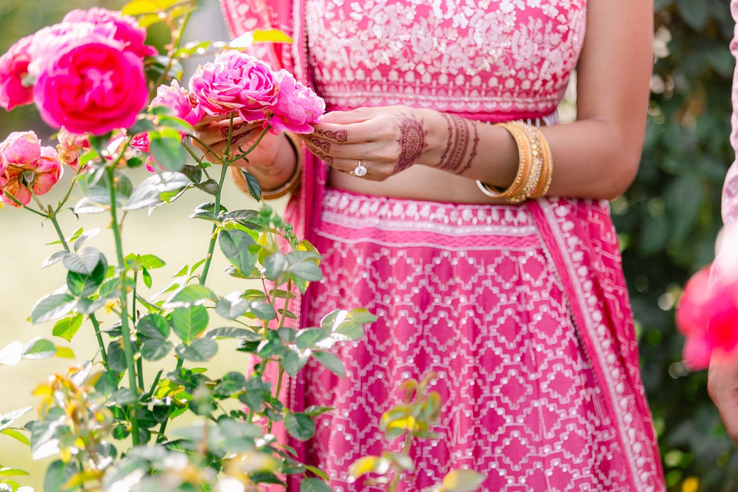 Close-up details of intricate pink embroidery and beadwork on traditional Indian wedding attire.