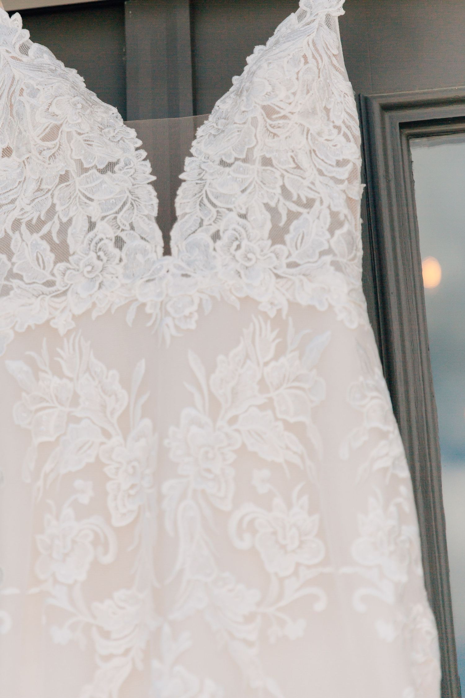 Close-up detail of intricate lace pattern on white wedding dress bodice.