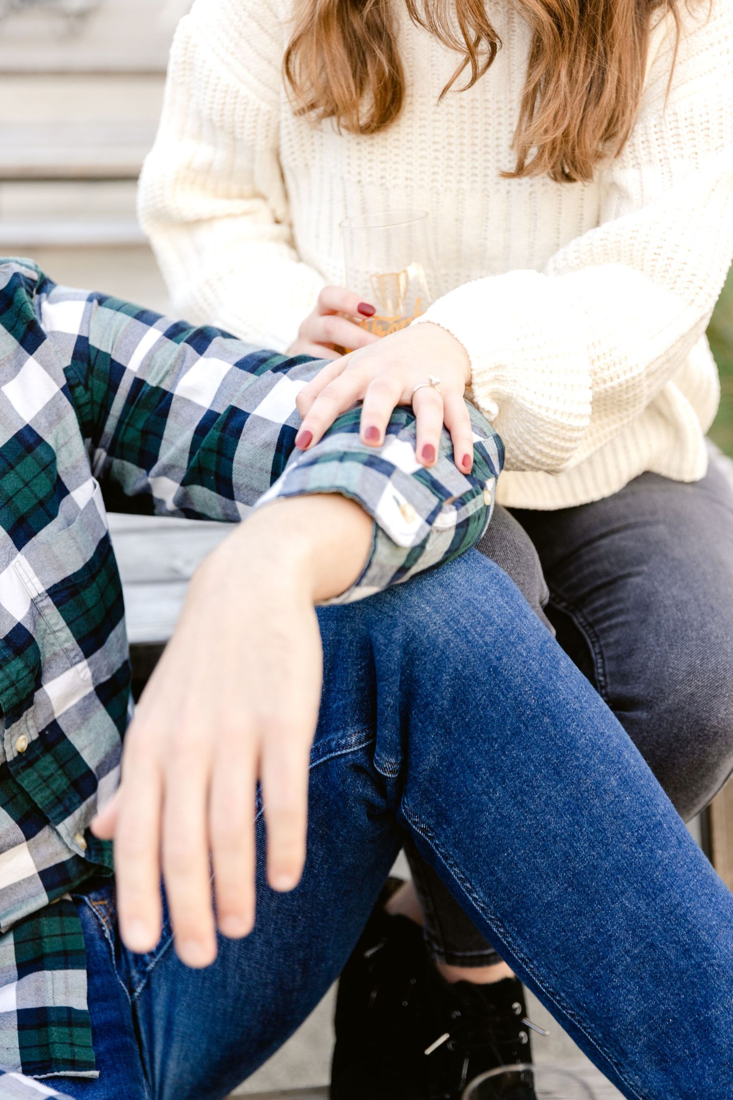 Close up of two people sitting together wearing coordinating plaid and knit sweaters in blue and cream.