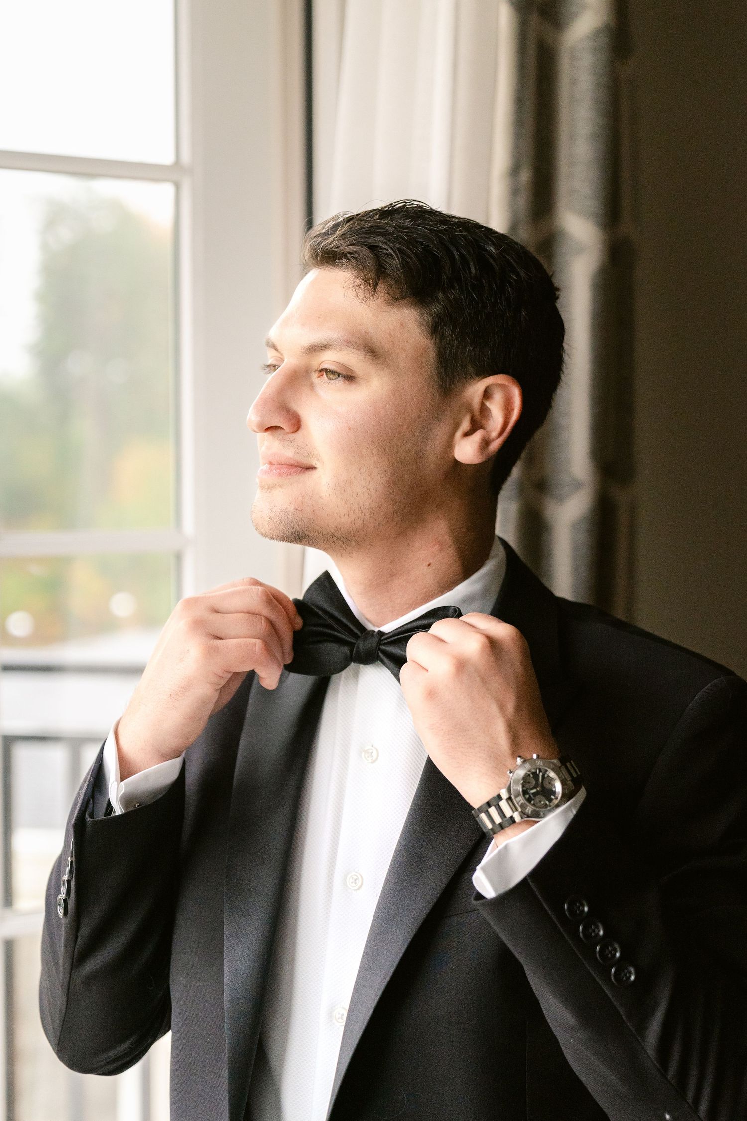 A series of formal portraits showing someone in a black tuxedo adjusting their collar and bow tie.