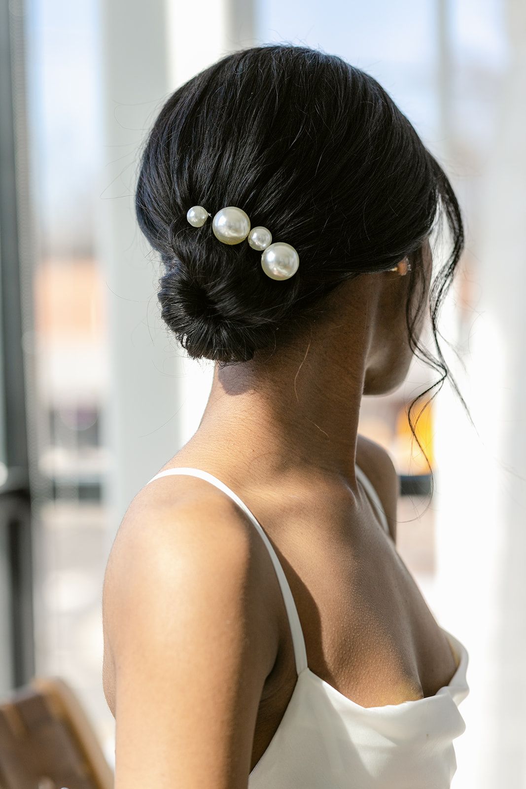 Pearl hair pins elegantly accent dark updo hairstyles in a bridal preparation scene.
