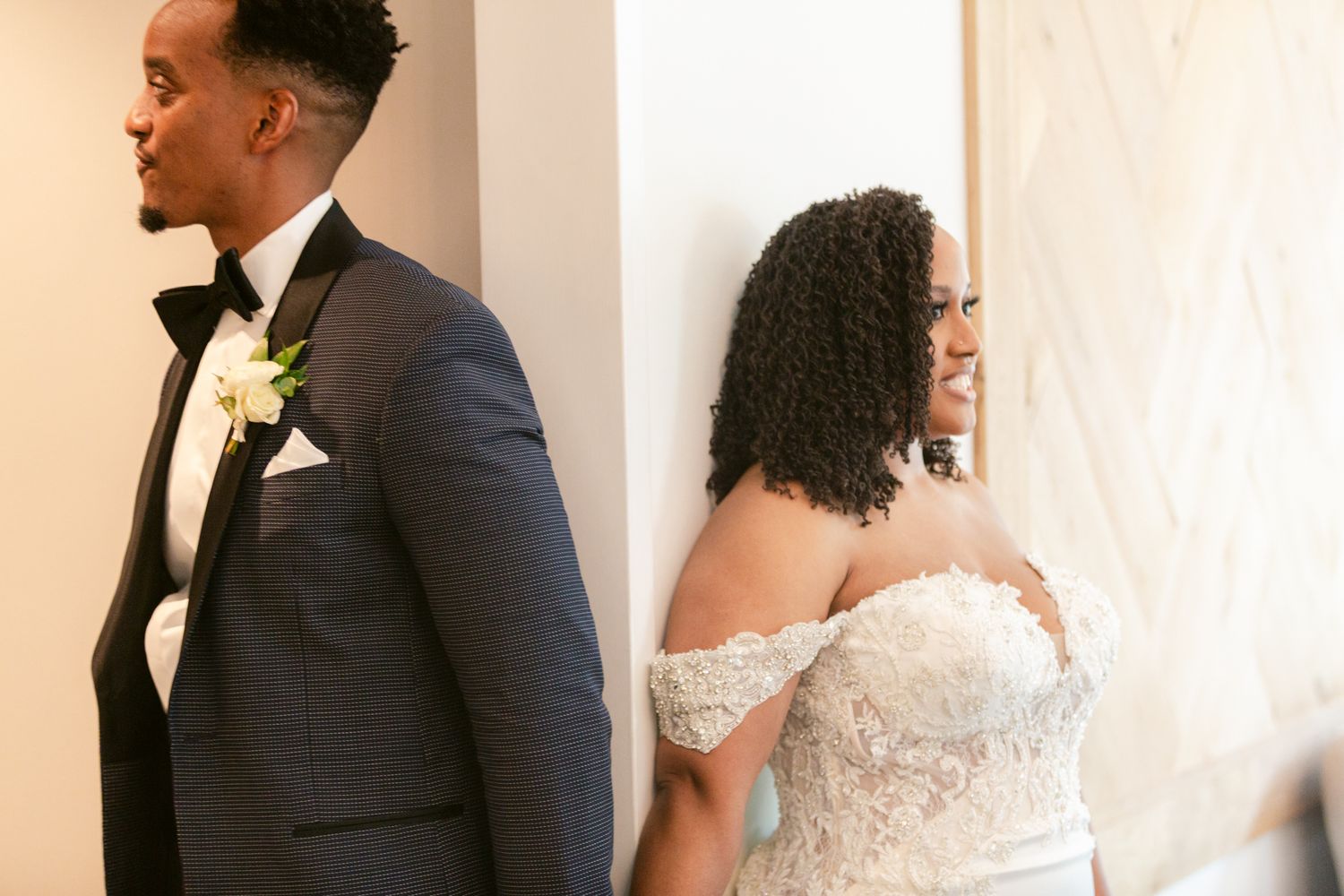 A bride and groom share a private first look moment before their wedding ceremony, separated by a white wall.