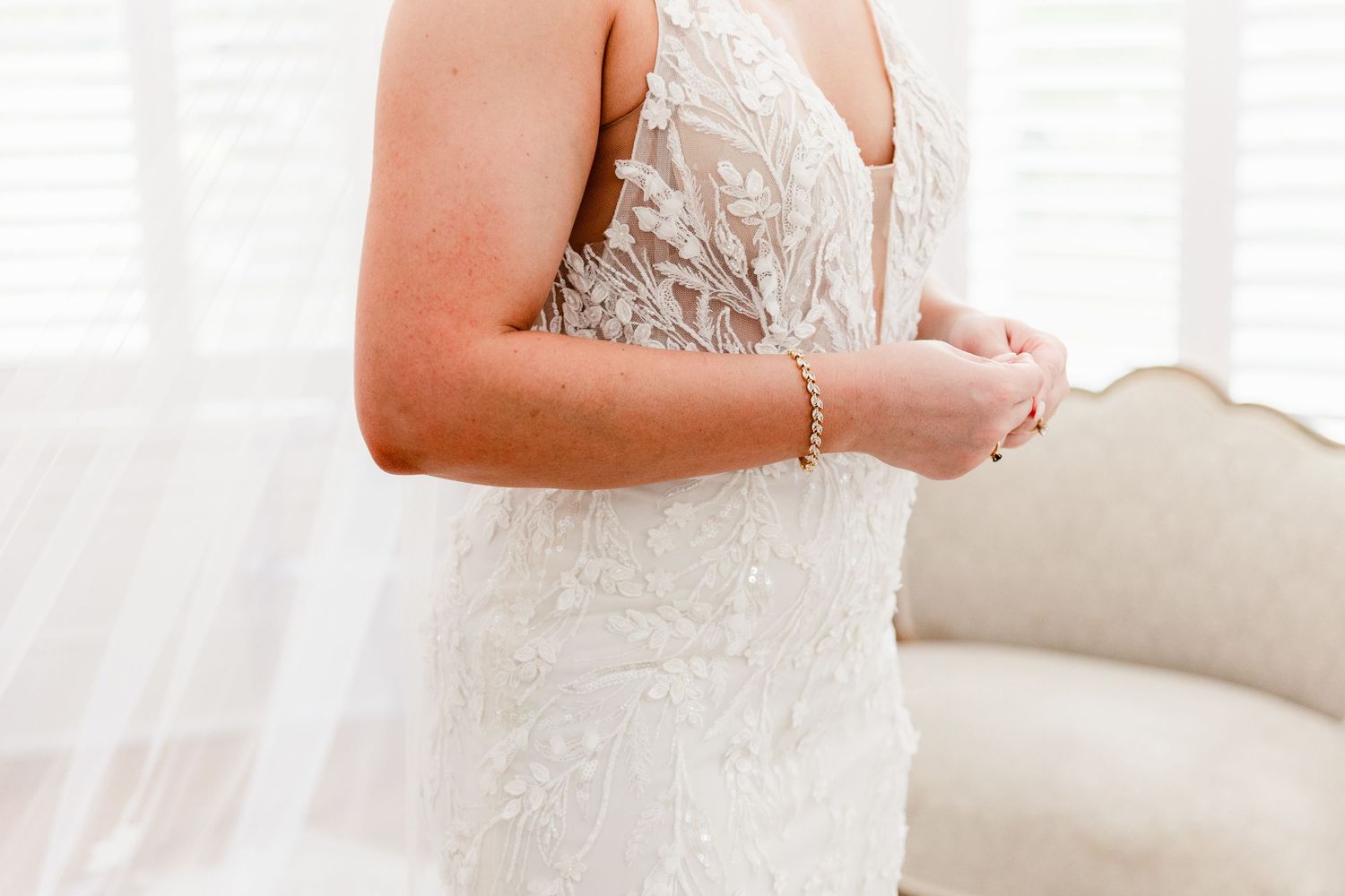 Close-up view of intricate lace details on a white wedding dress with delicate beading and floral patterns.