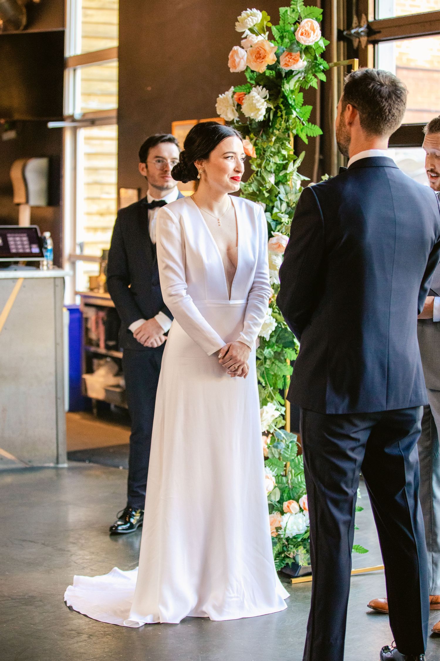 A couple in wedding attire shares a first look moment in a rustic venue with floral decorations.