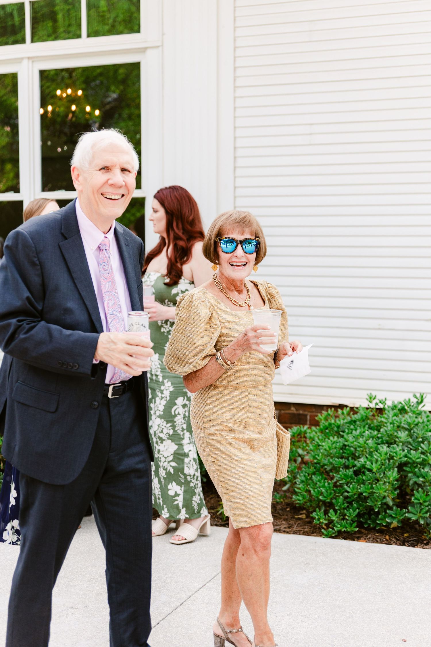 Couples dancing together on a white patio during an outdoor celebration.