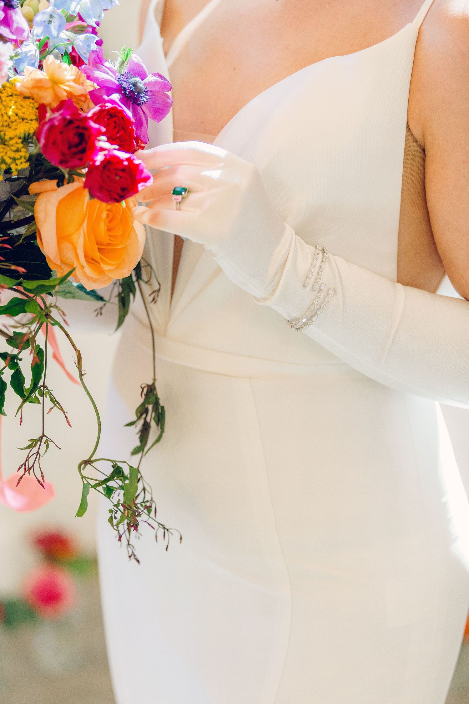 Close-up of vibrant pink and orange wedding bouquets against white bridal gowns.