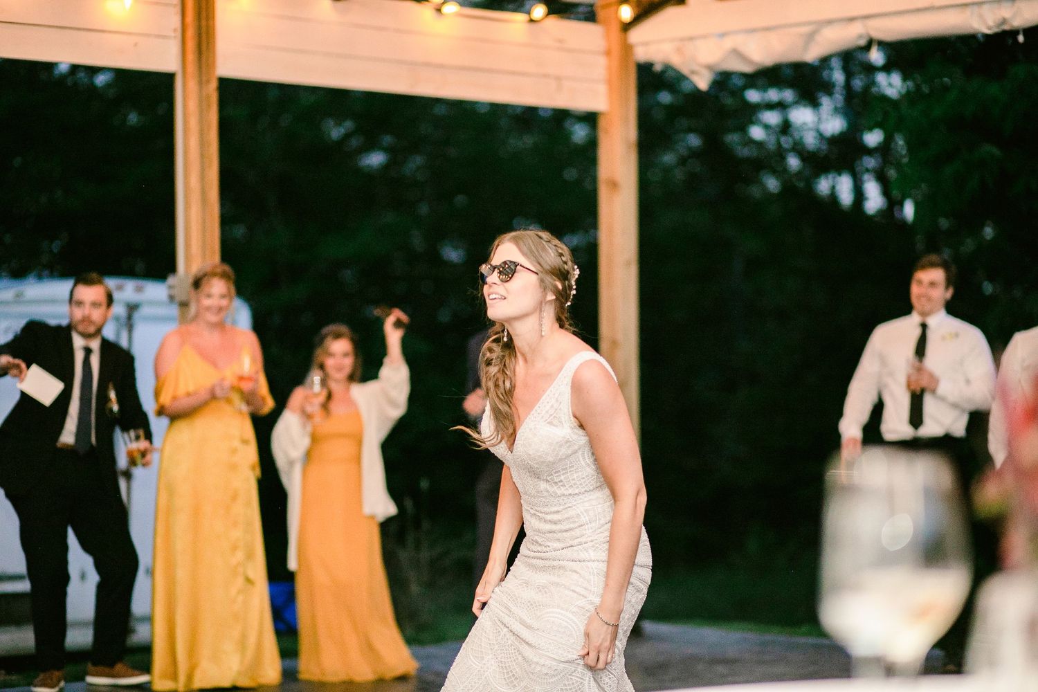 A bride in a fitted white dress dances during the wedding reception under a wooden pavilion.