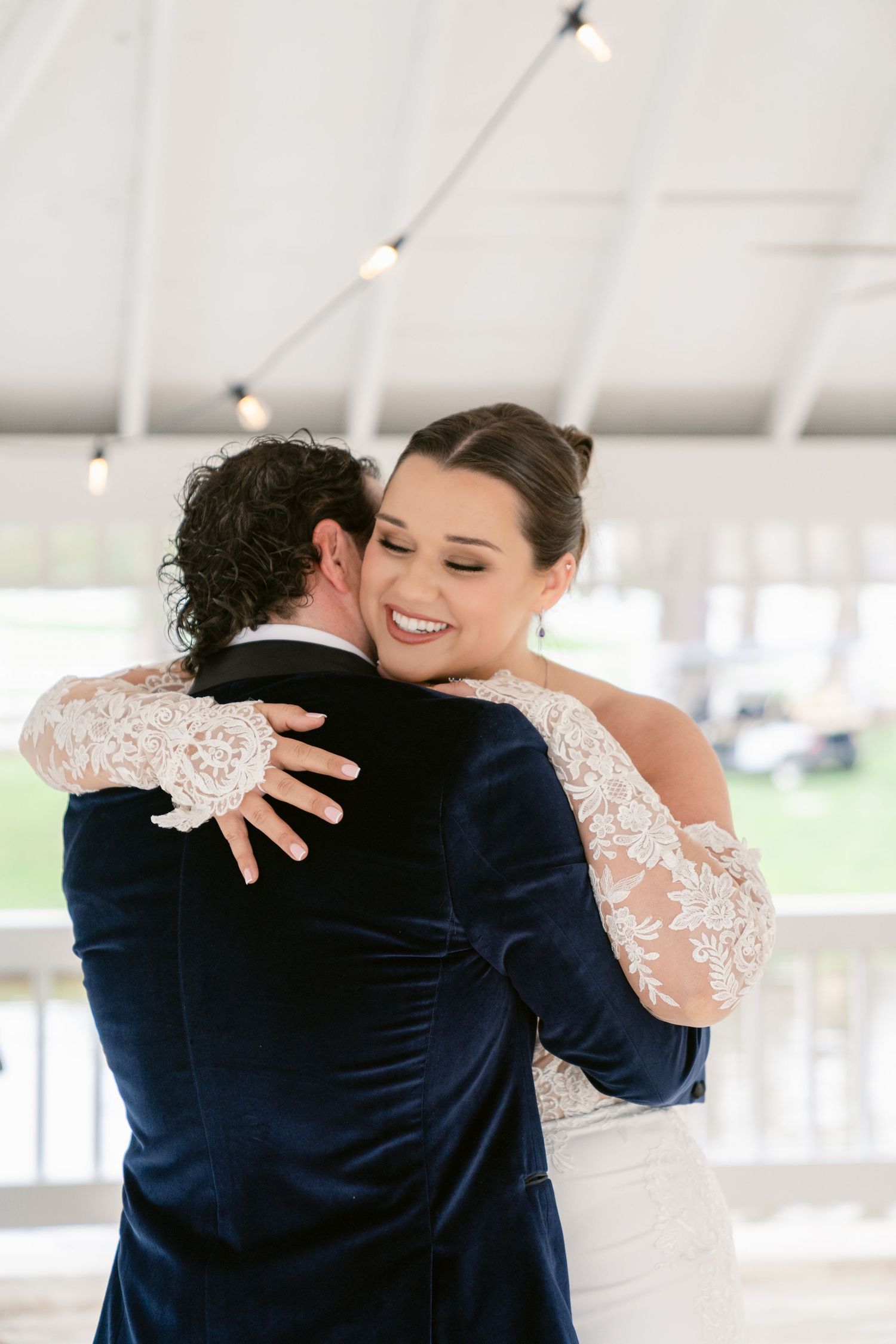 A joyful couple embraces while dancing under a white tent at their wedding reception.
