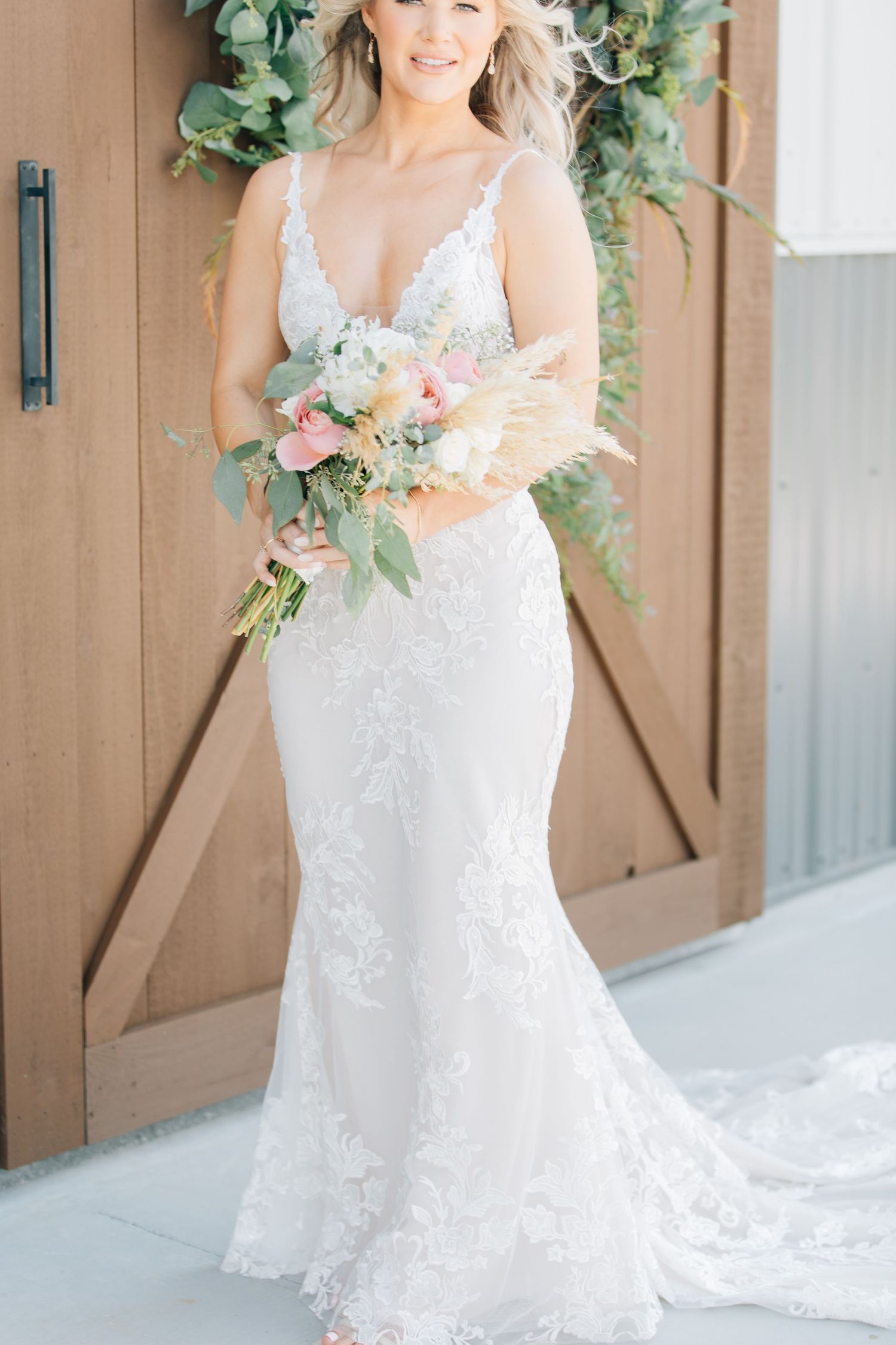 Elegant lace wedding dress with v-neckline and soft pastel bouquet.