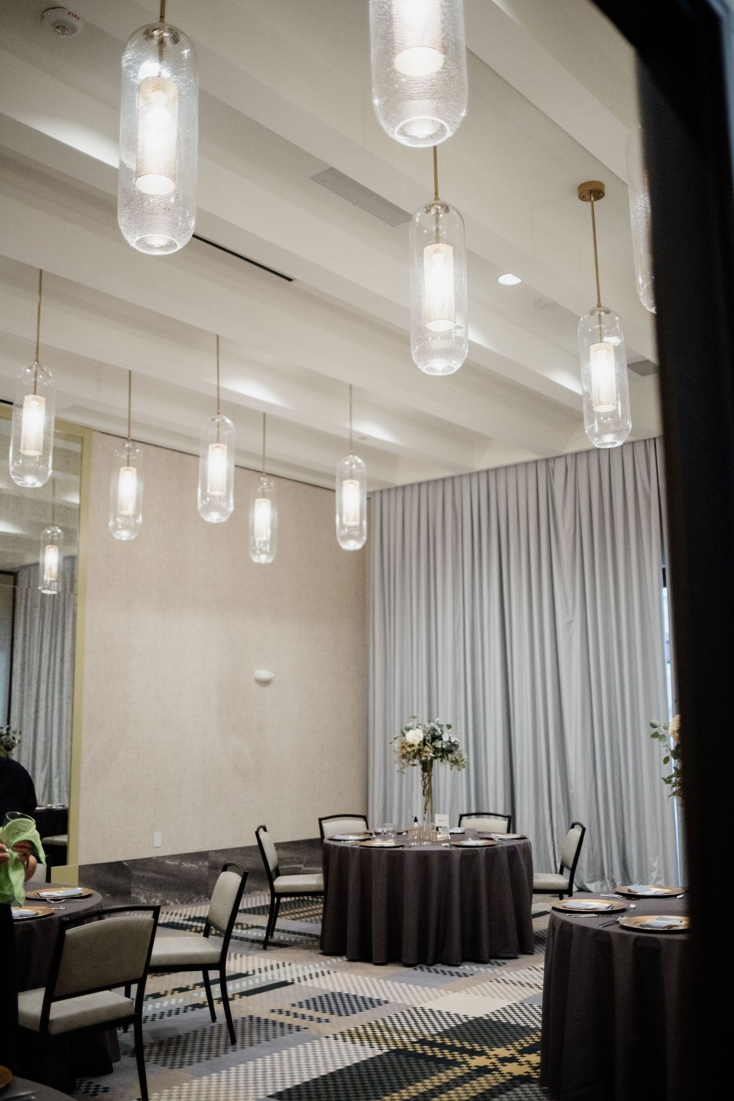 Modern reception room with hanging glass pendant lights and round tables.