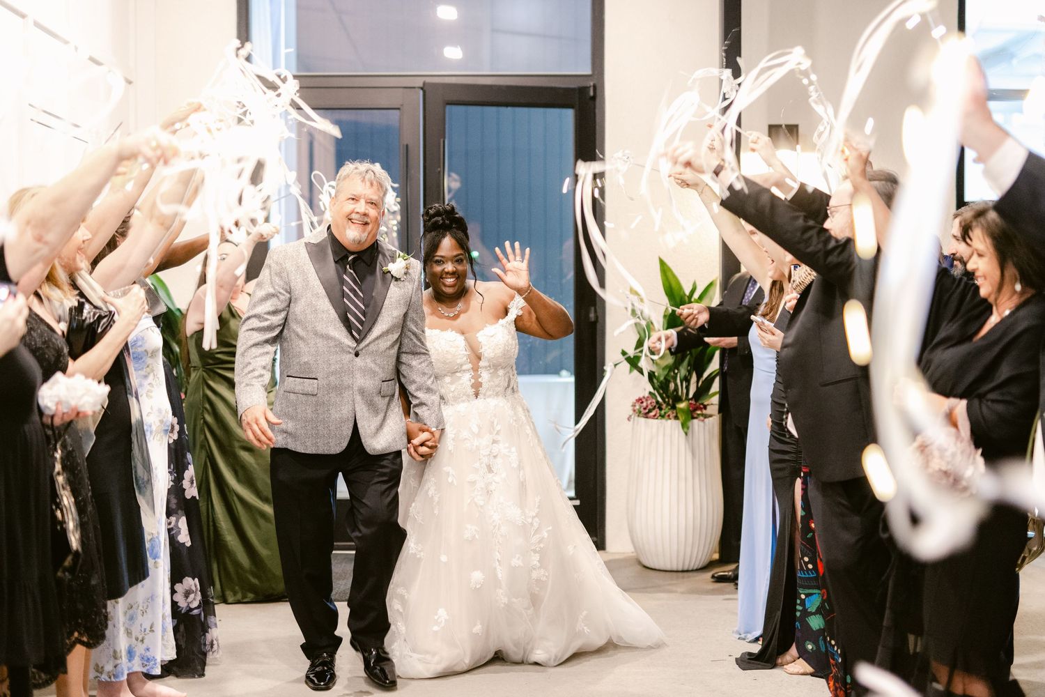 Wedding guests raise their hands in celebration as the newlyweds dance during their reception.