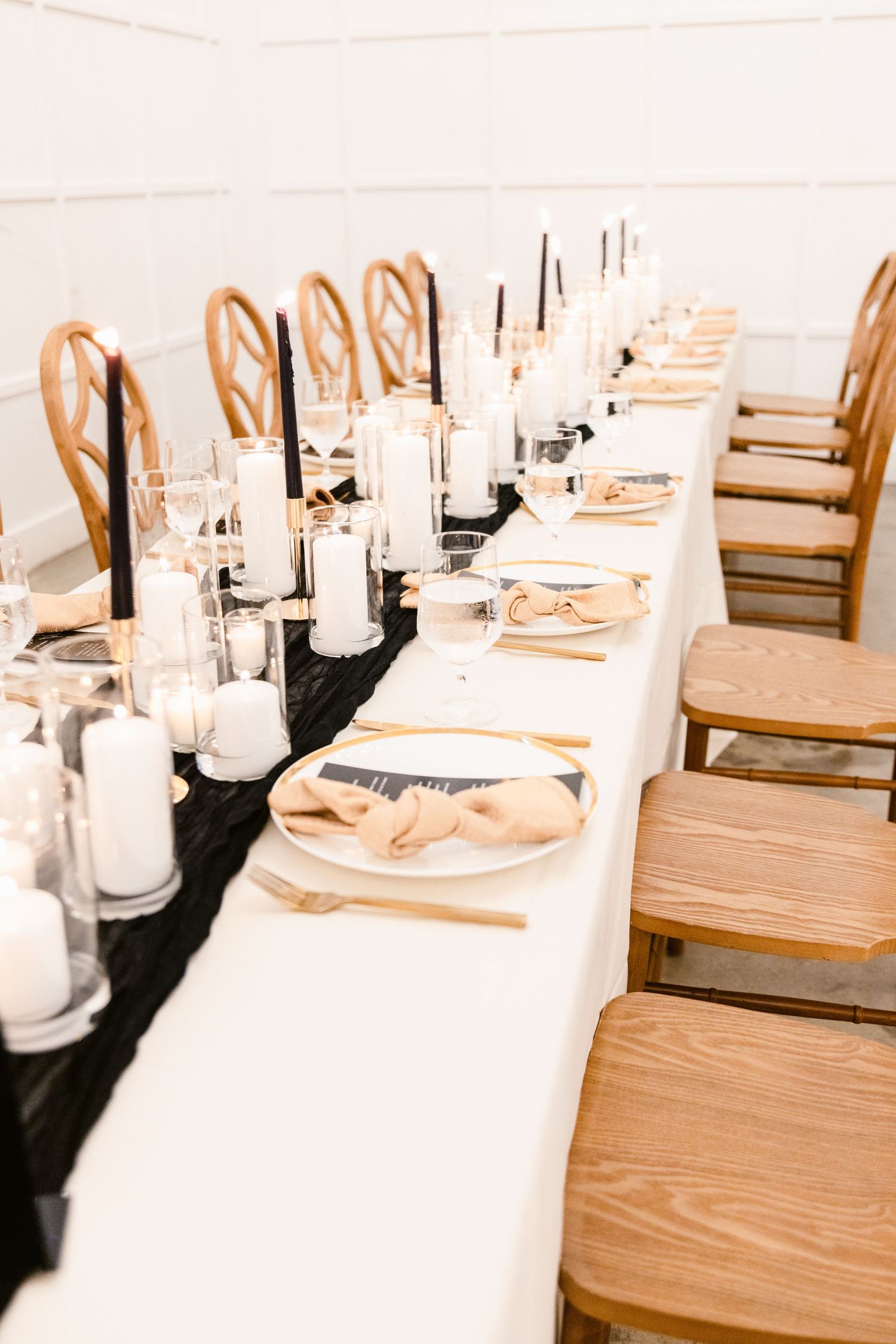 Elegant table settings with white linens and wooden chairs at a formal event.