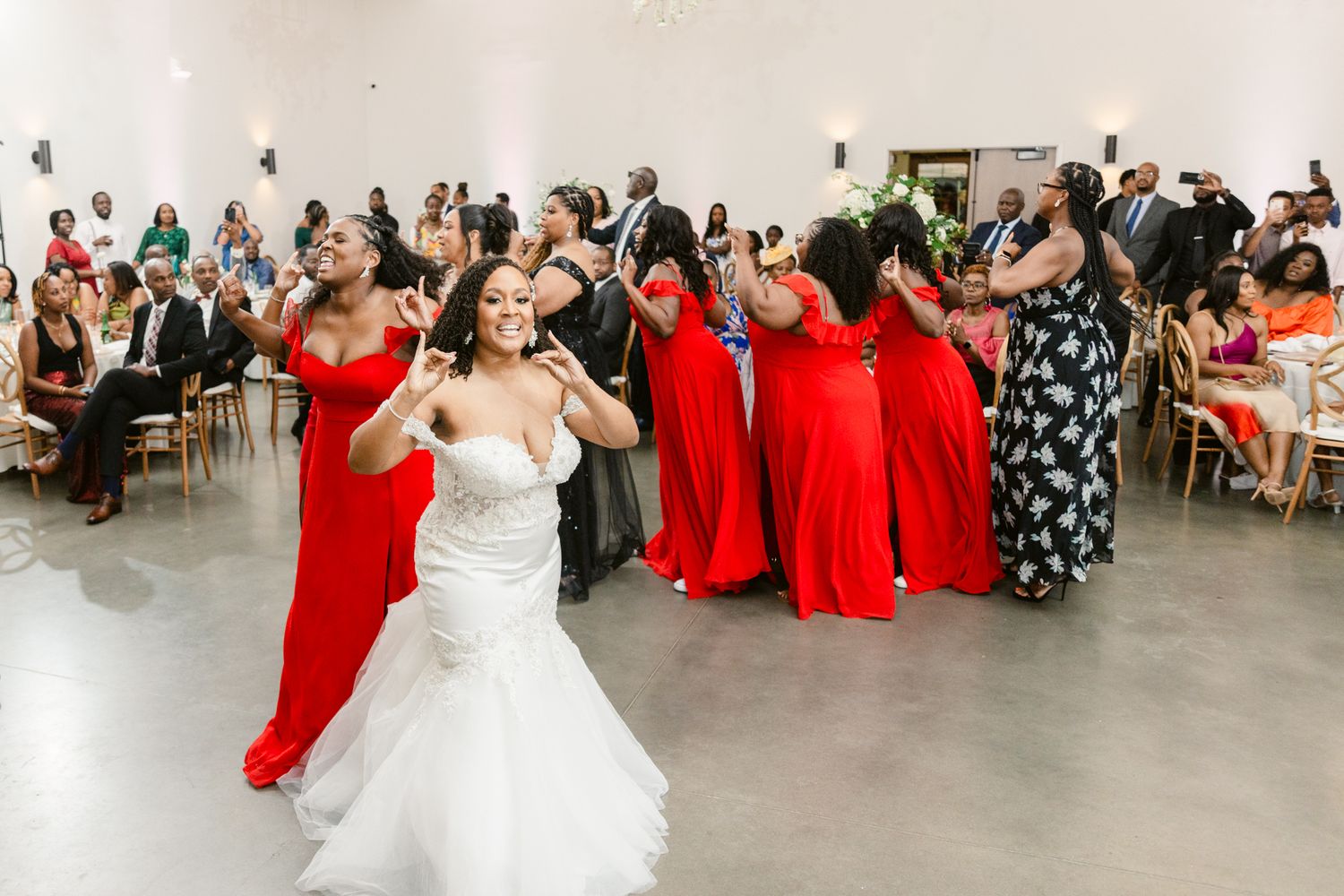 Wedding party and guests celebrating in an elegant white reception space.