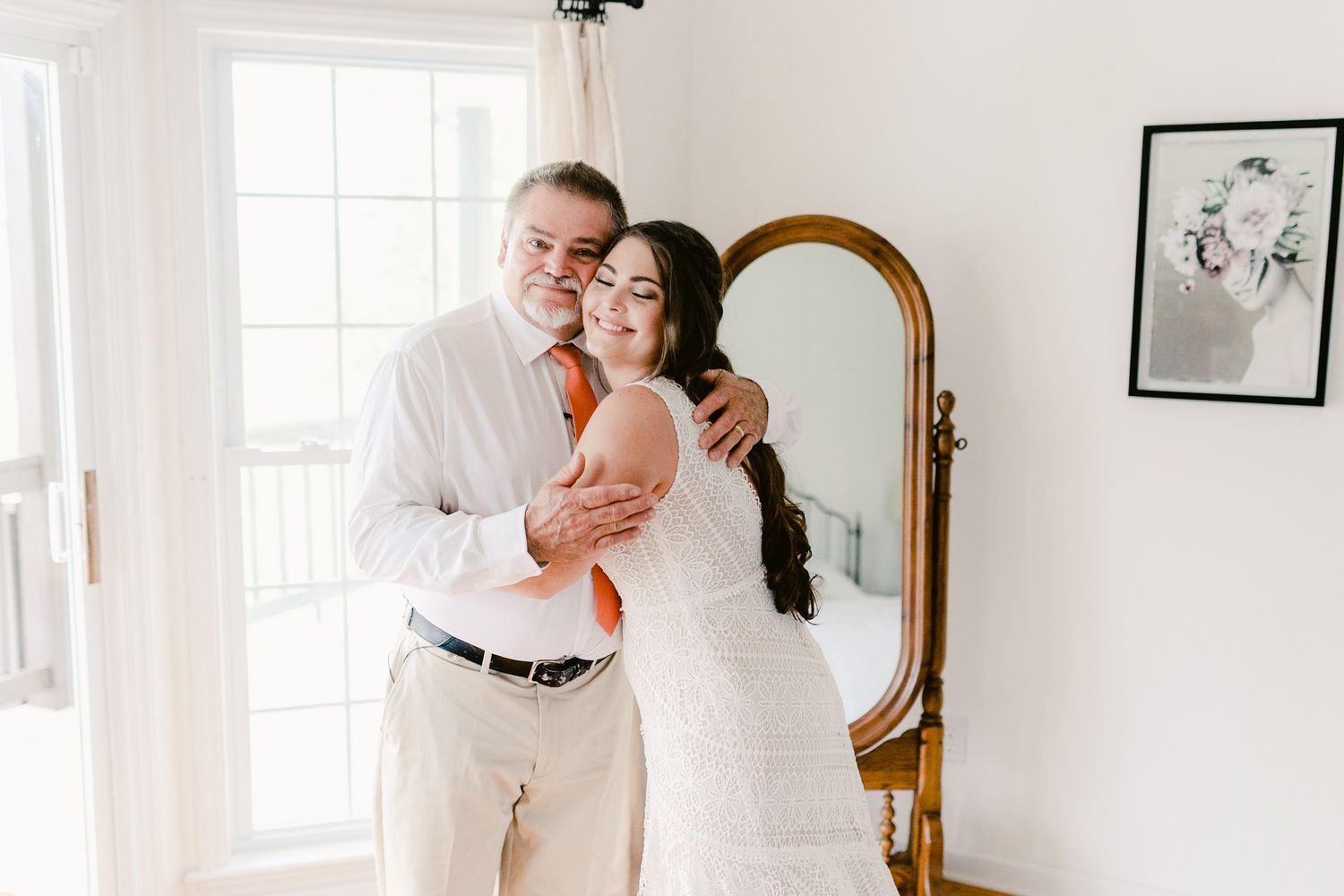 A tender moment shared between two people in formal attire next to an elegant gold-framed mirror.