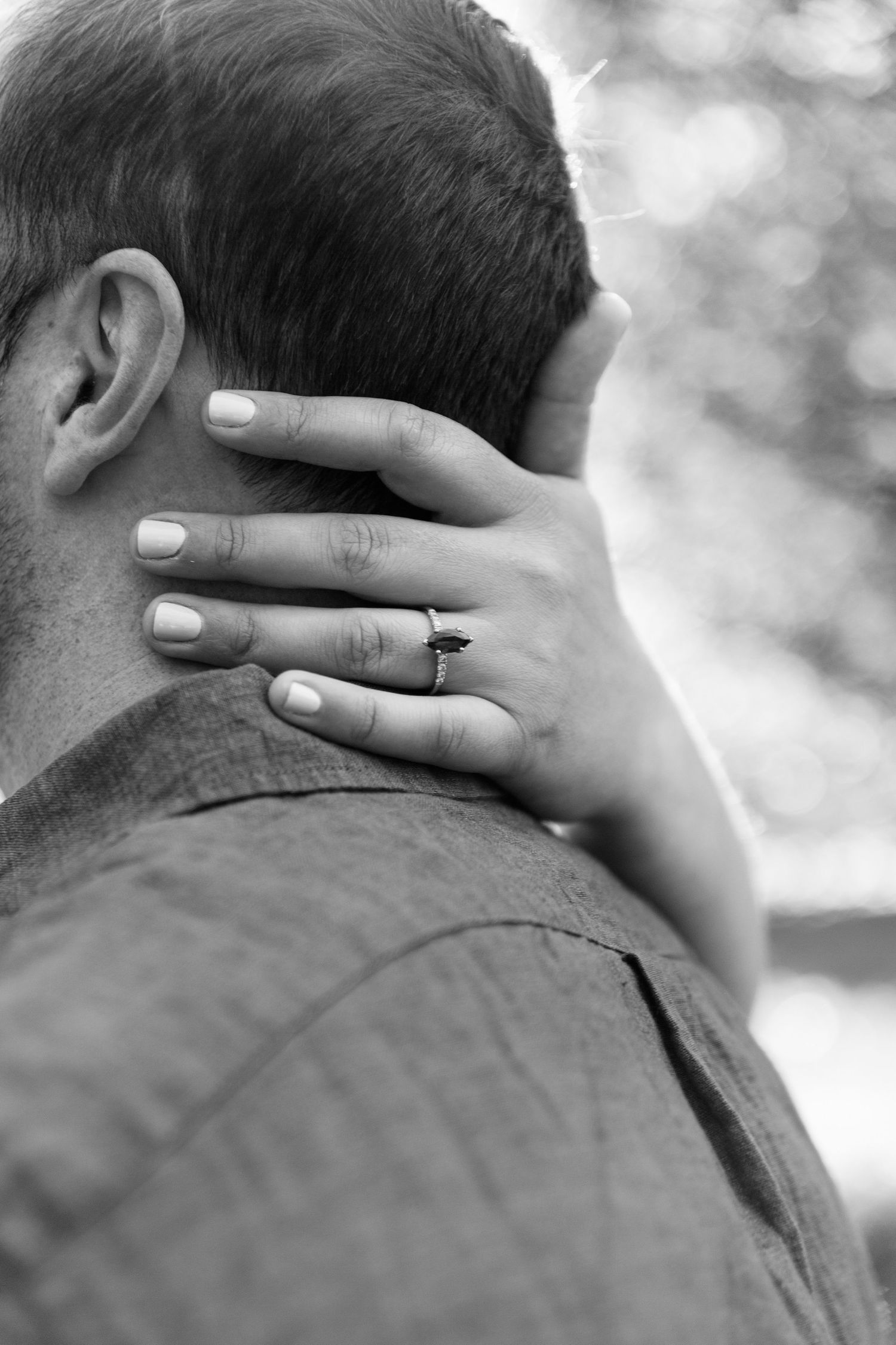 Black and white close-up shots showing hands with rings gently touching the back of someone's neck.