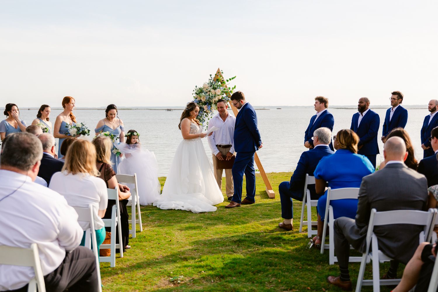 Panoramic sequence of a seaside wedding ceremony with guests seated in blue chairs overlooking the ocean.