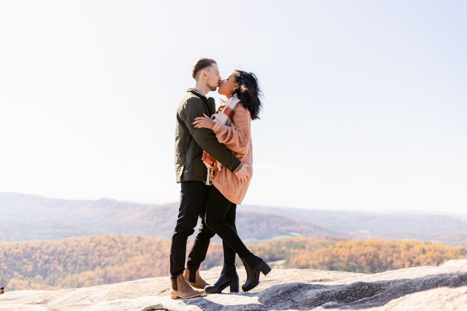 A couple shares an intimate moment together on a scenic mountain overlook during autumn.
