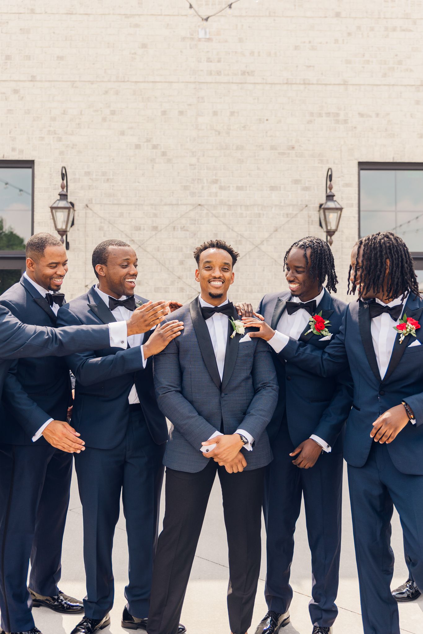 Groomsmen in navy blue suits and bow ties celebrate together at a wedding ceremony.