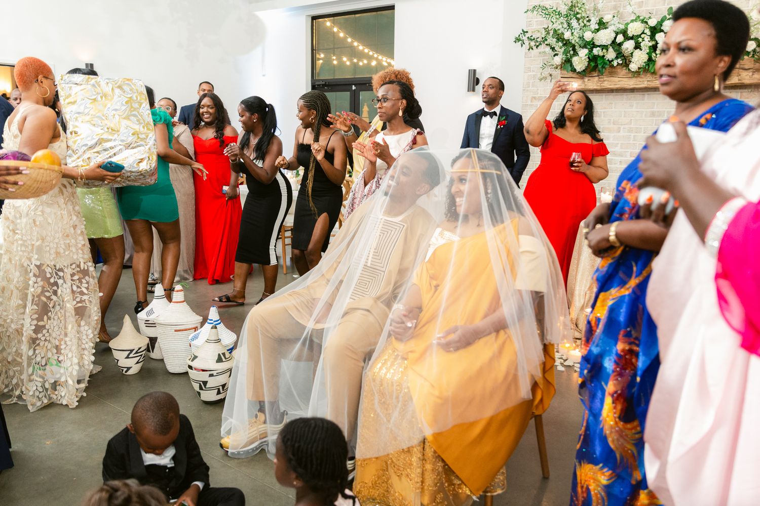 Wedding guests in colorful formal attire dancing and celebrating at the reception.