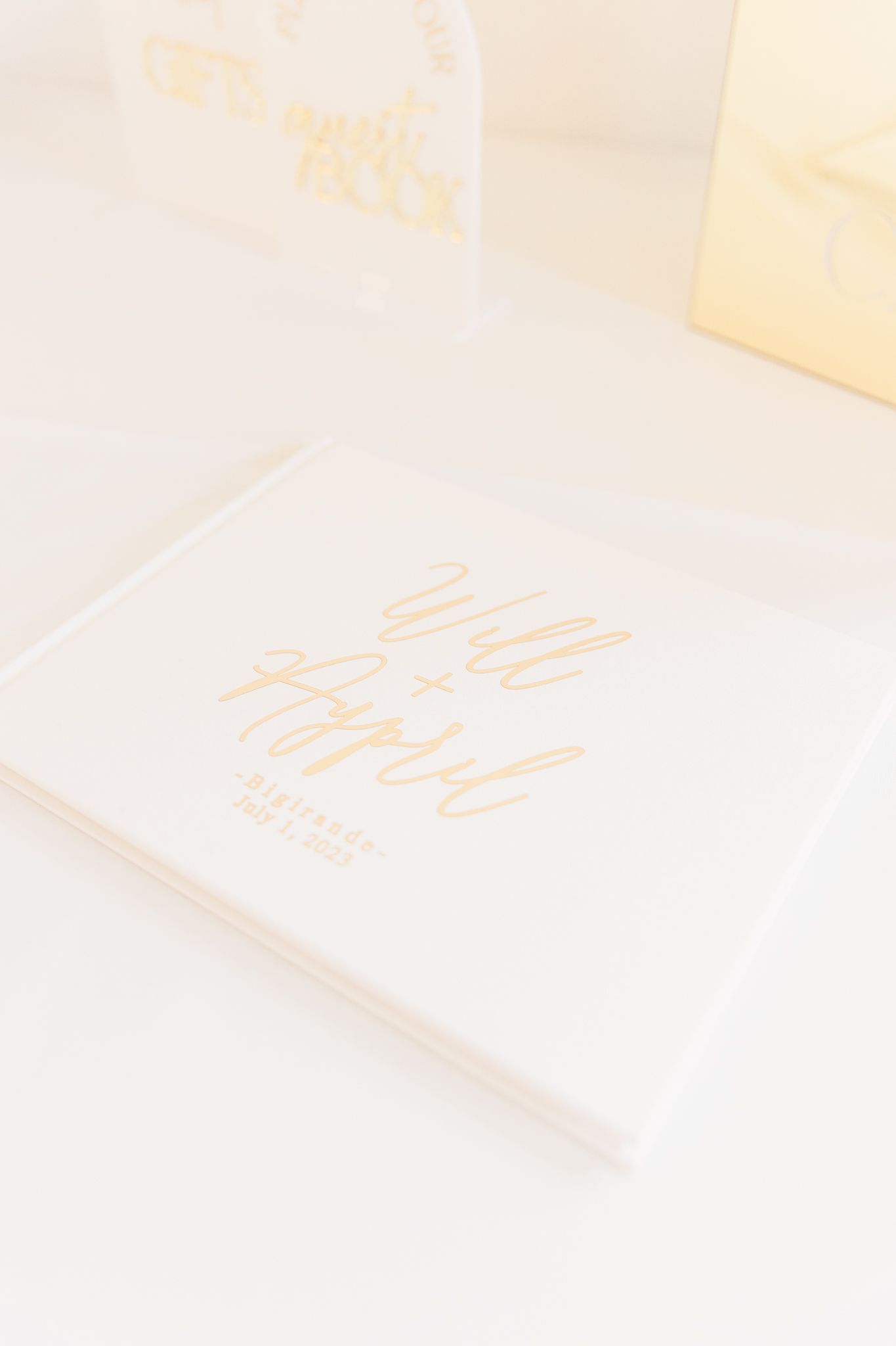 Soft focus close-up of white paper or stationery with delicate gold text or embossing.