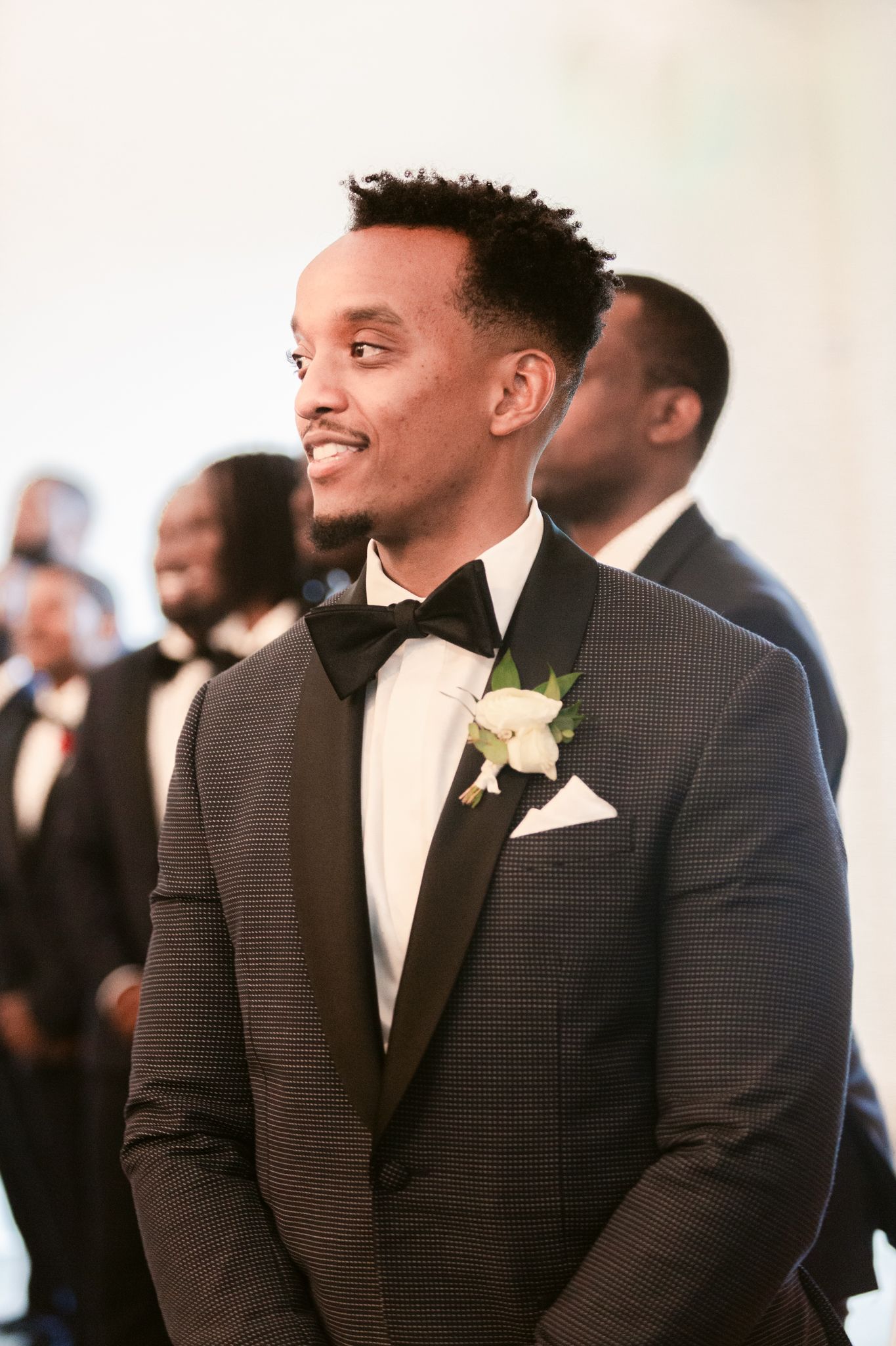 Wedding guests in dark suits share joyful moments during a formal celebration.
