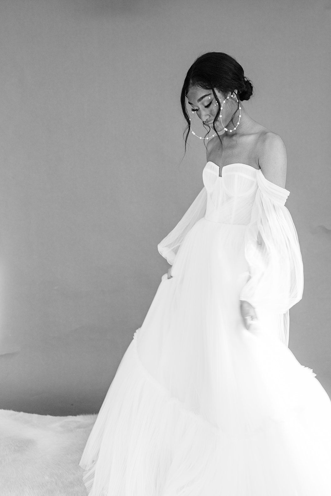 A series of black and white photographs showing a person in a flowing white dress lying down in artistic poses.