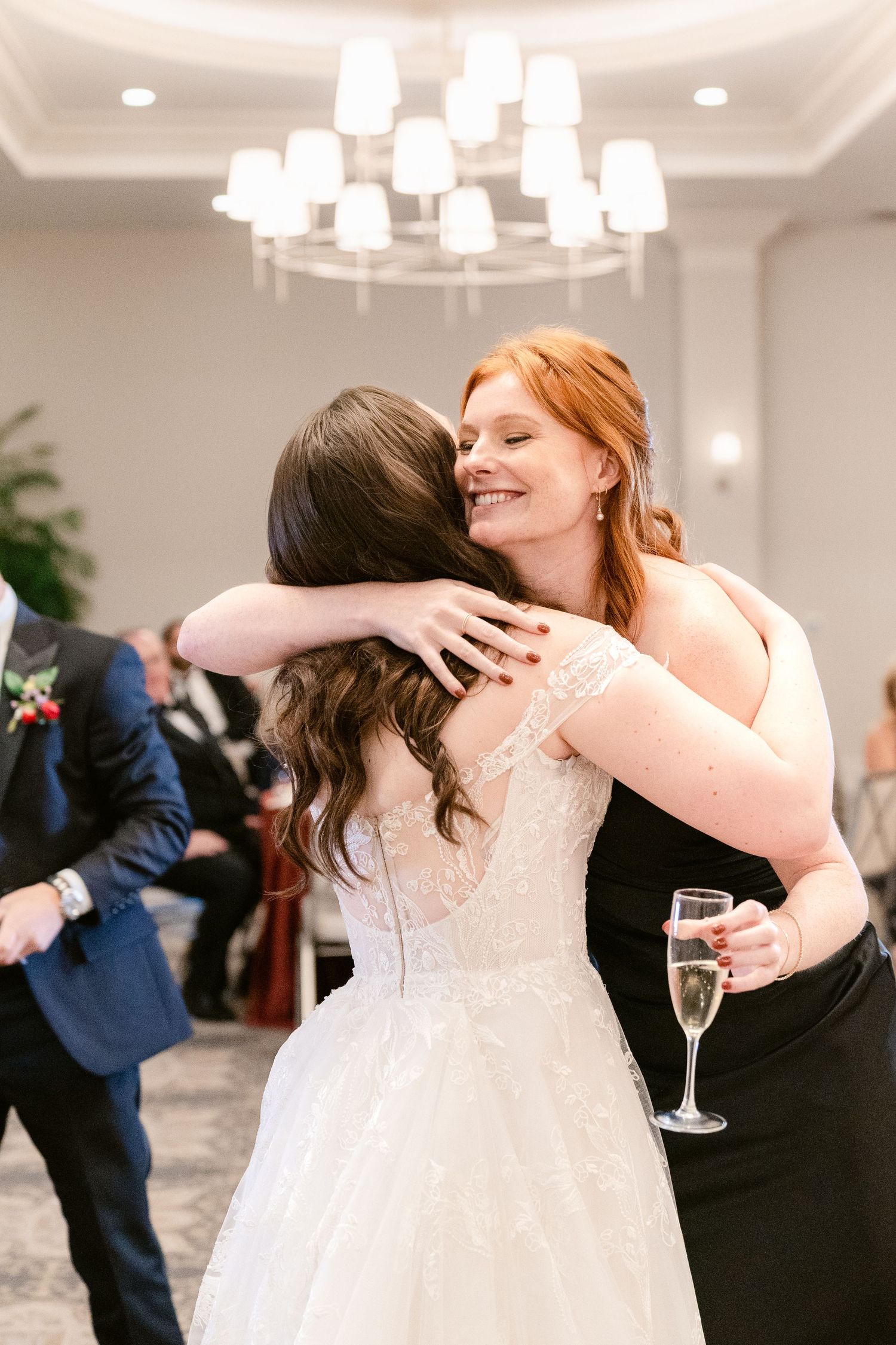 Mother and daughter share an emotional embrace during a wedding reception in an elegant ballroom.